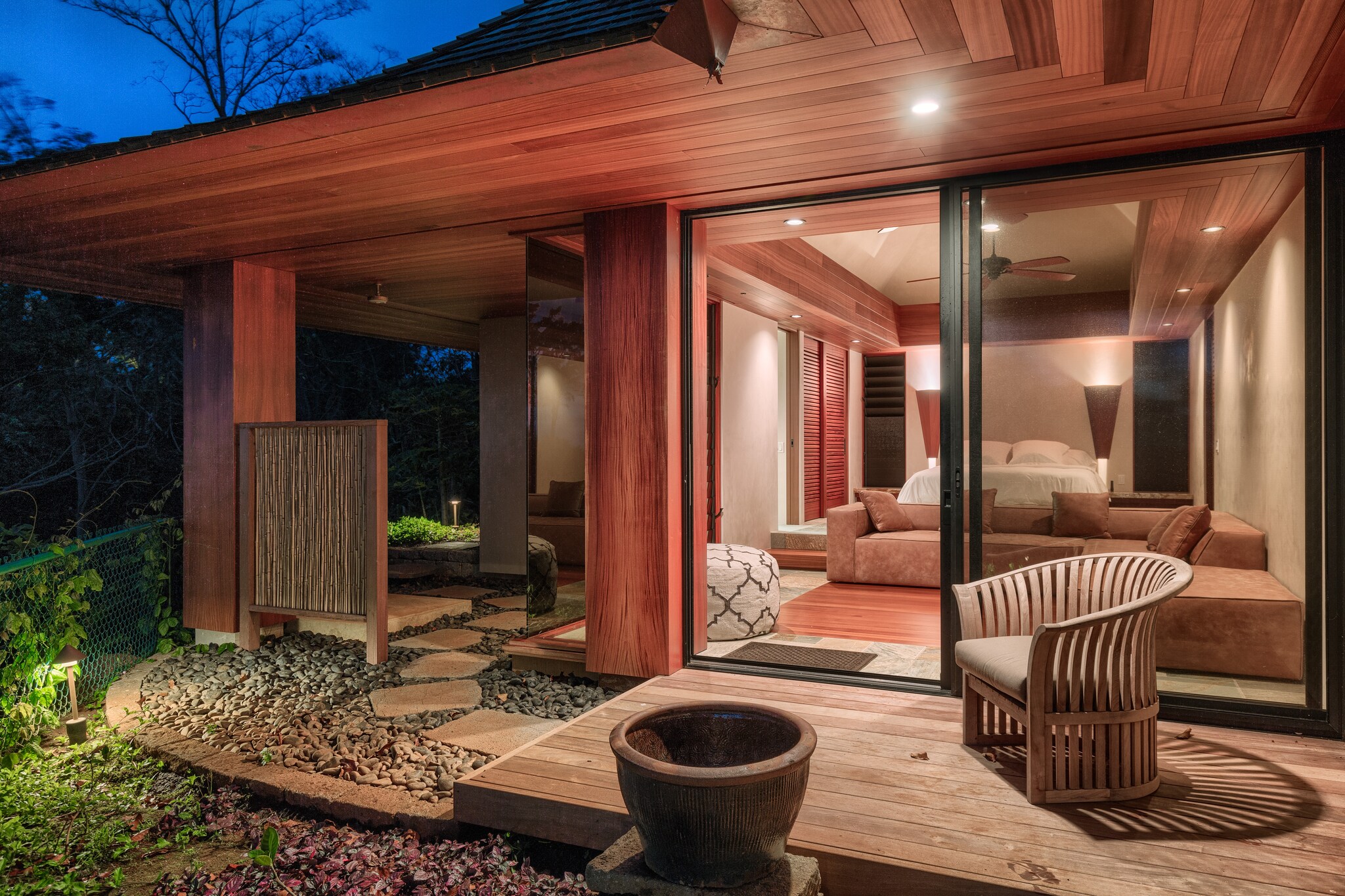 Exterior view of patio outside bedroom with expansive windows at night