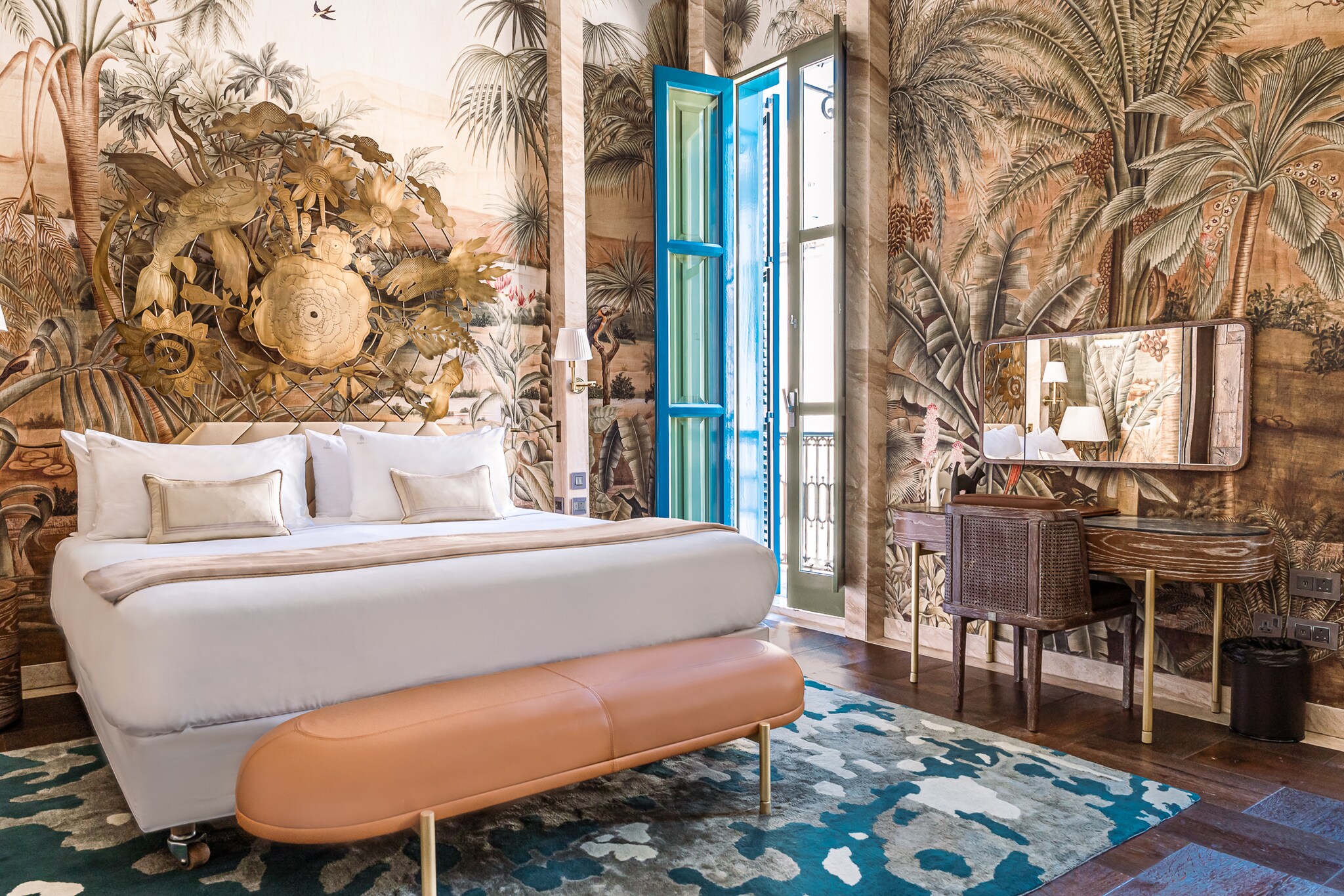 A Grand Residence Bedroom is painted with murals of island plants. A wire and gold-colored flower fixture is fixed above the white bed.