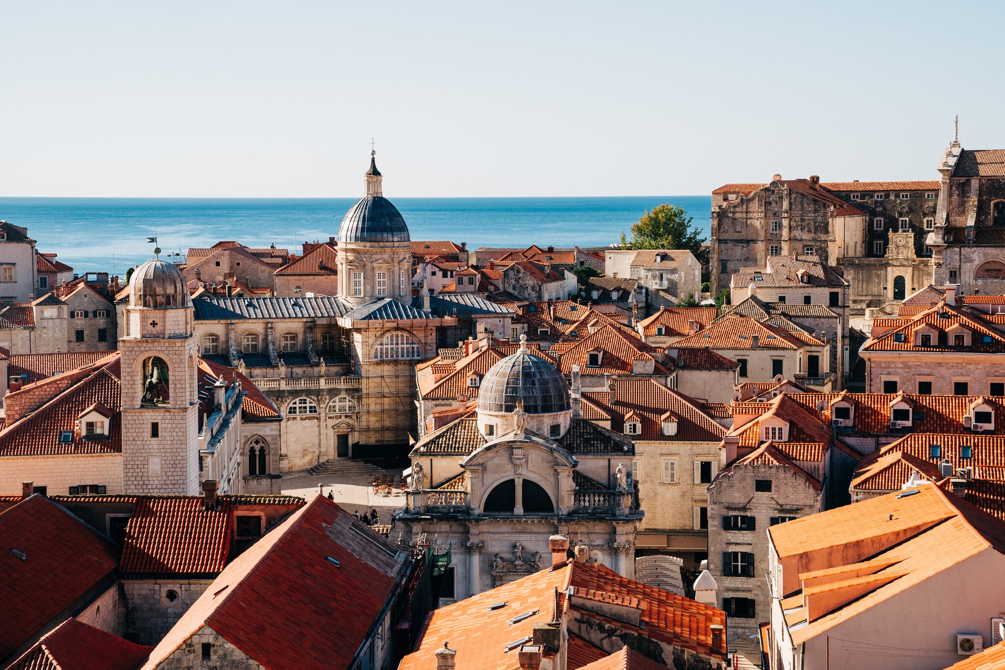 View over the orange rooftops of Dubrovnik’s Old Town, broken up by the blue roof and dome of a monastery.