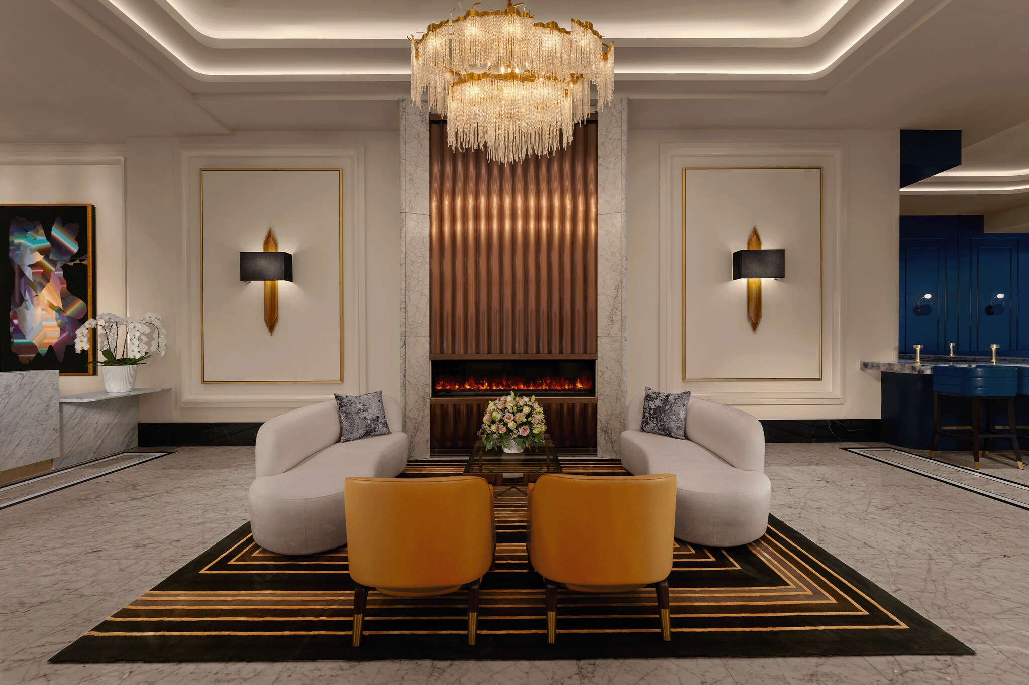 In the lobby of AZUR Legacy Collection Hotel, gray couches and brown chairs cluster on a large black rug with concentric golden squares.