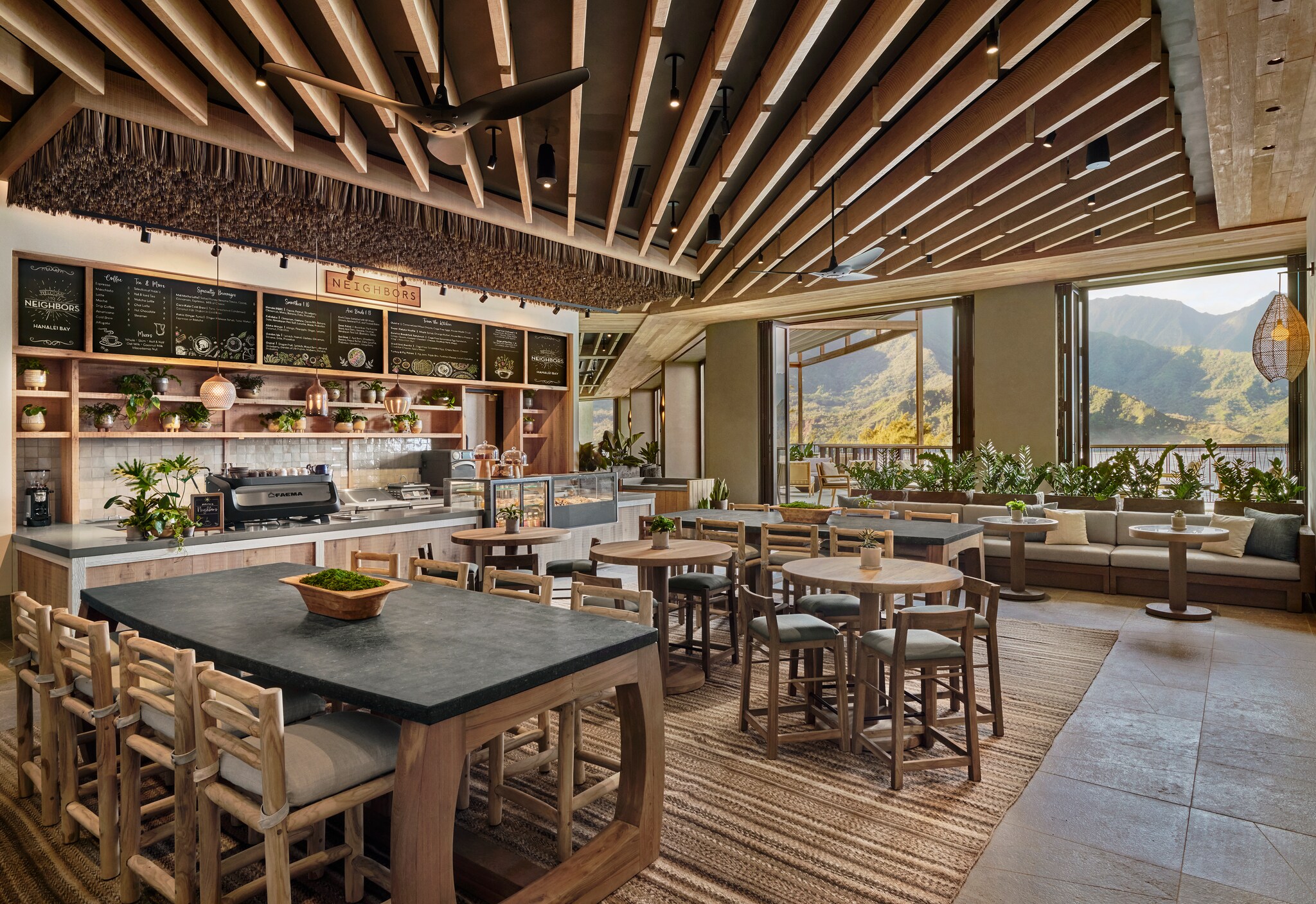 The Neighbors café has high ceilings with exposed wooden beams; ample chairs, tables, and couches; and chalk menu boards above the counter. 