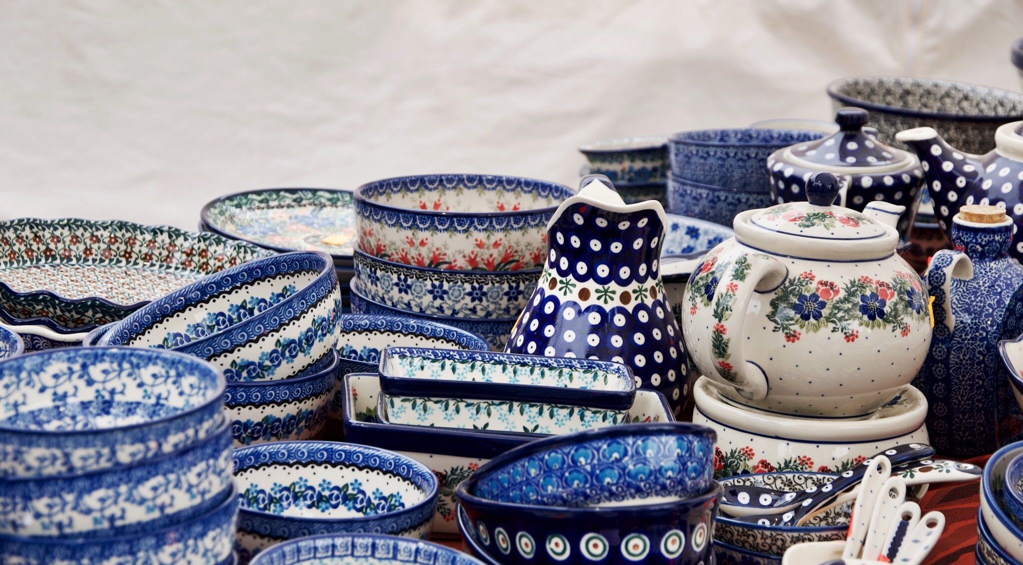 Stacks of delicately painted bowls are clustered together, with pitchers and teapots decorated with flowers and spots.