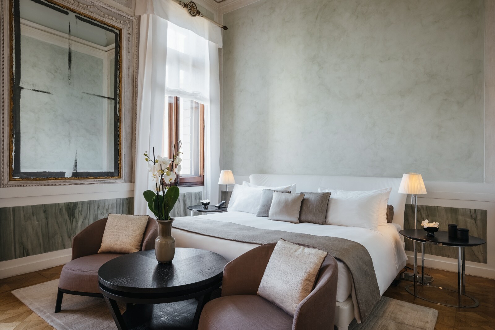 Coccina’s Apartment at Aman Venice is decorated in understated colors, including mottled gray walls and mauve chairs at the foot of the bed.