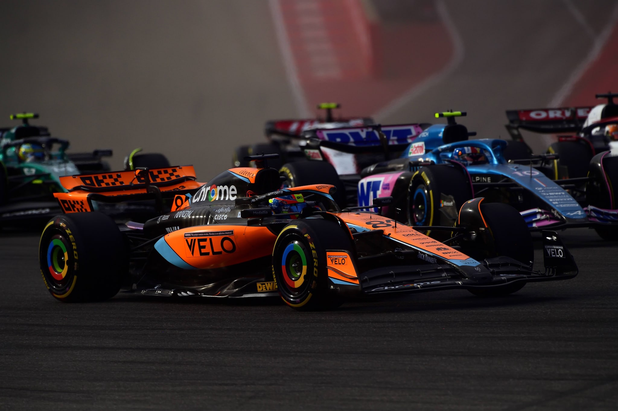 Colorful racecars covered in sponsor logos jockey for position as they race.