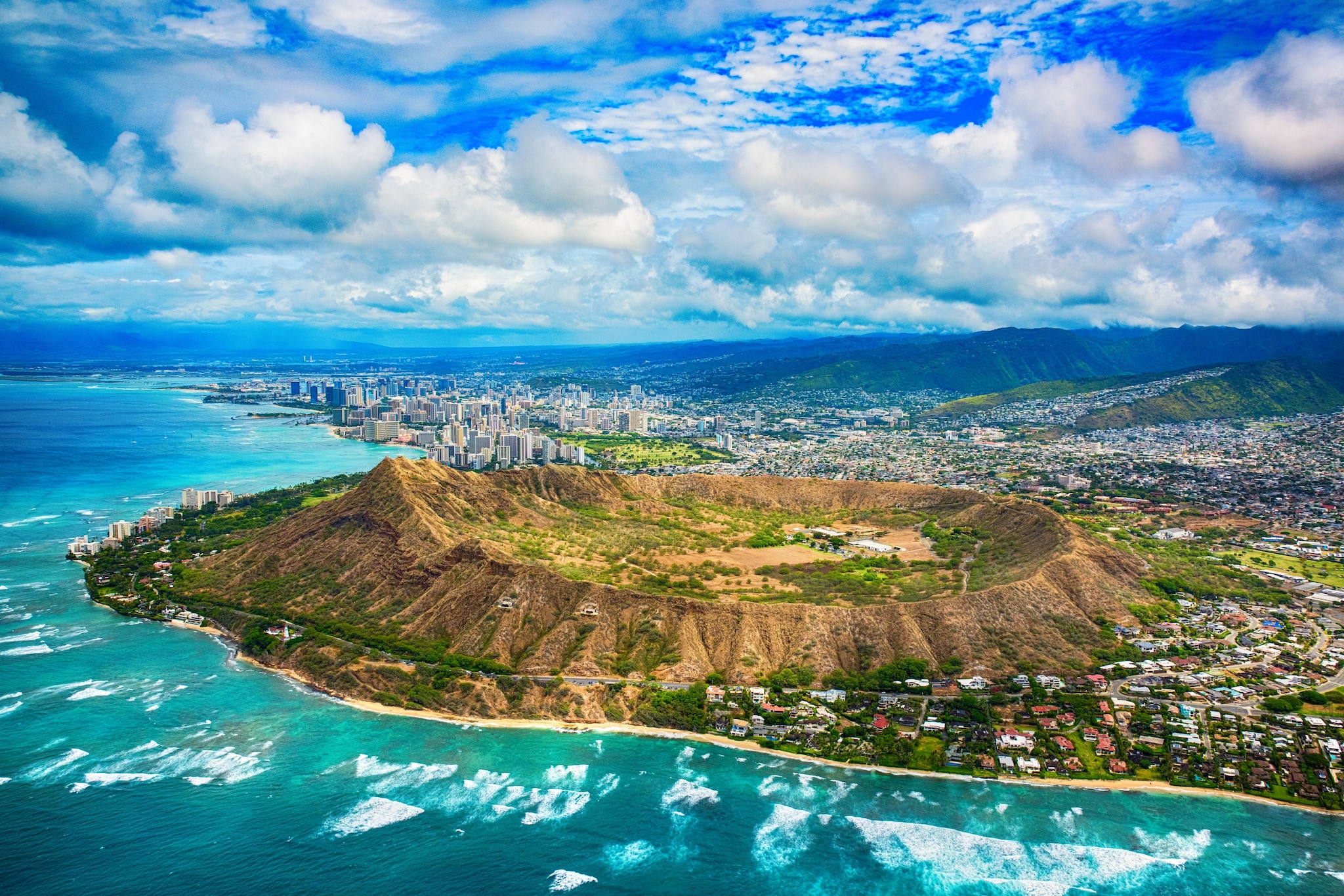 Aerial view of Diamond Head, a huge, extinct sandy-brown volcano overgrown with shrubbery and popular with hikers in the Honolulu area.