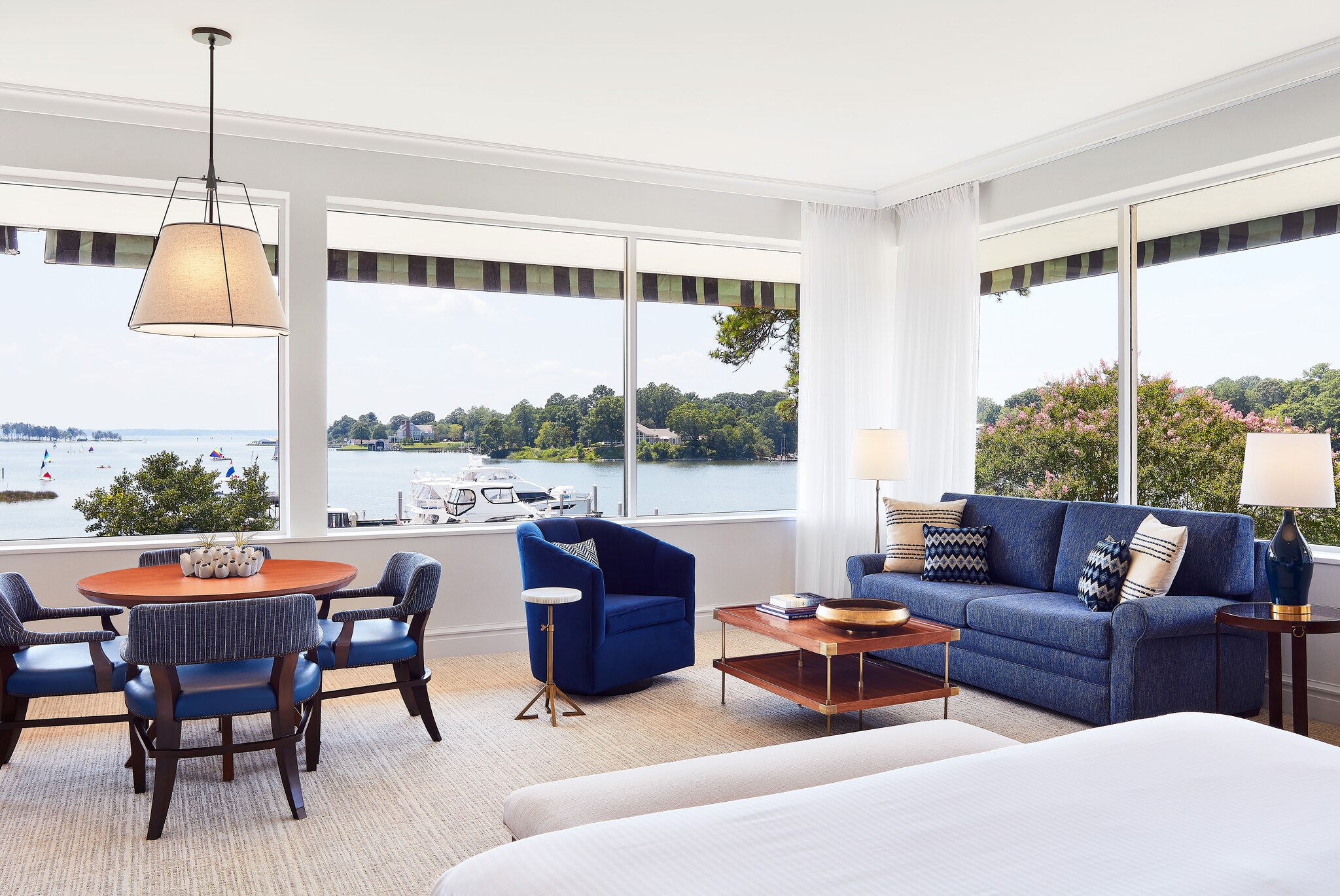 The living area in the Ashburn Suites has deep blue furniture with red wood accents, and wide windows overlooking the water.