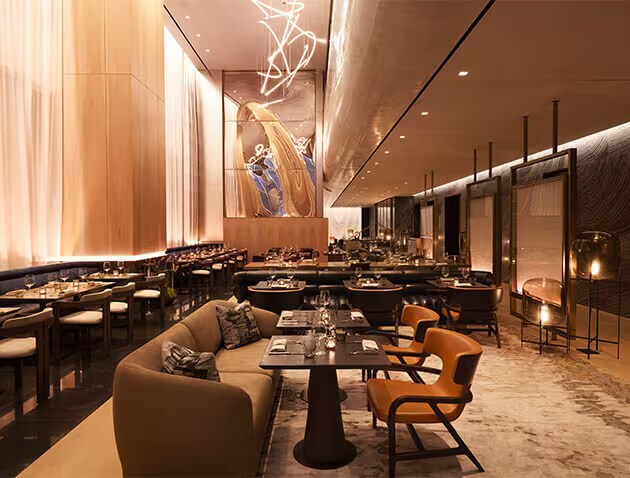 Interior of a restaurant with comfortable couch seating and large, bell-like candleholders.