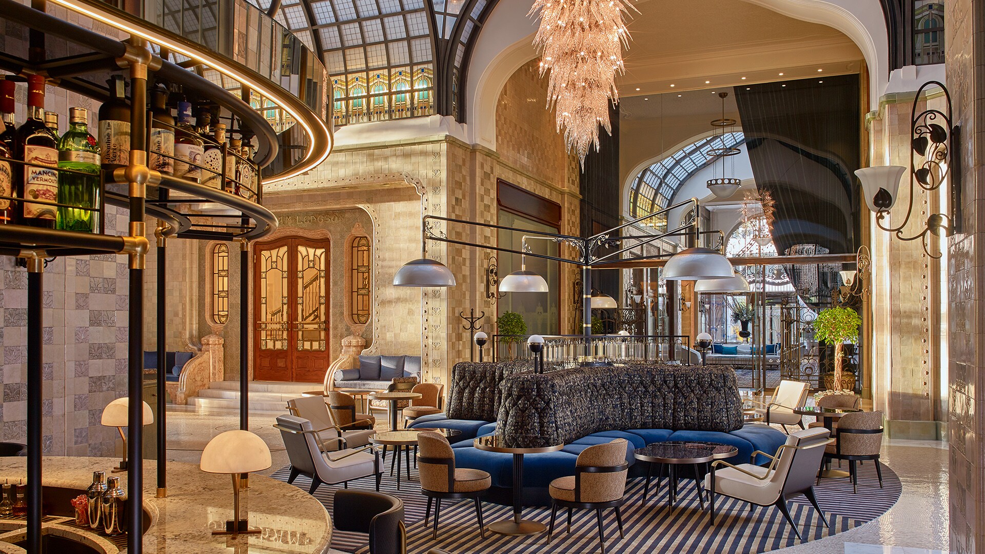 Múzsa, the cocktail bar at Four Seasons Hotel Gresham Palace Budapest, has an array of benches and chairs under high, arched glass ceilings.