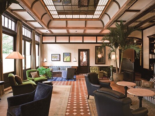 The lobby of The Greenwich Hotel has terracotta tile floors, velvet and leather armchairs, and gridded light panels on the ceiling.