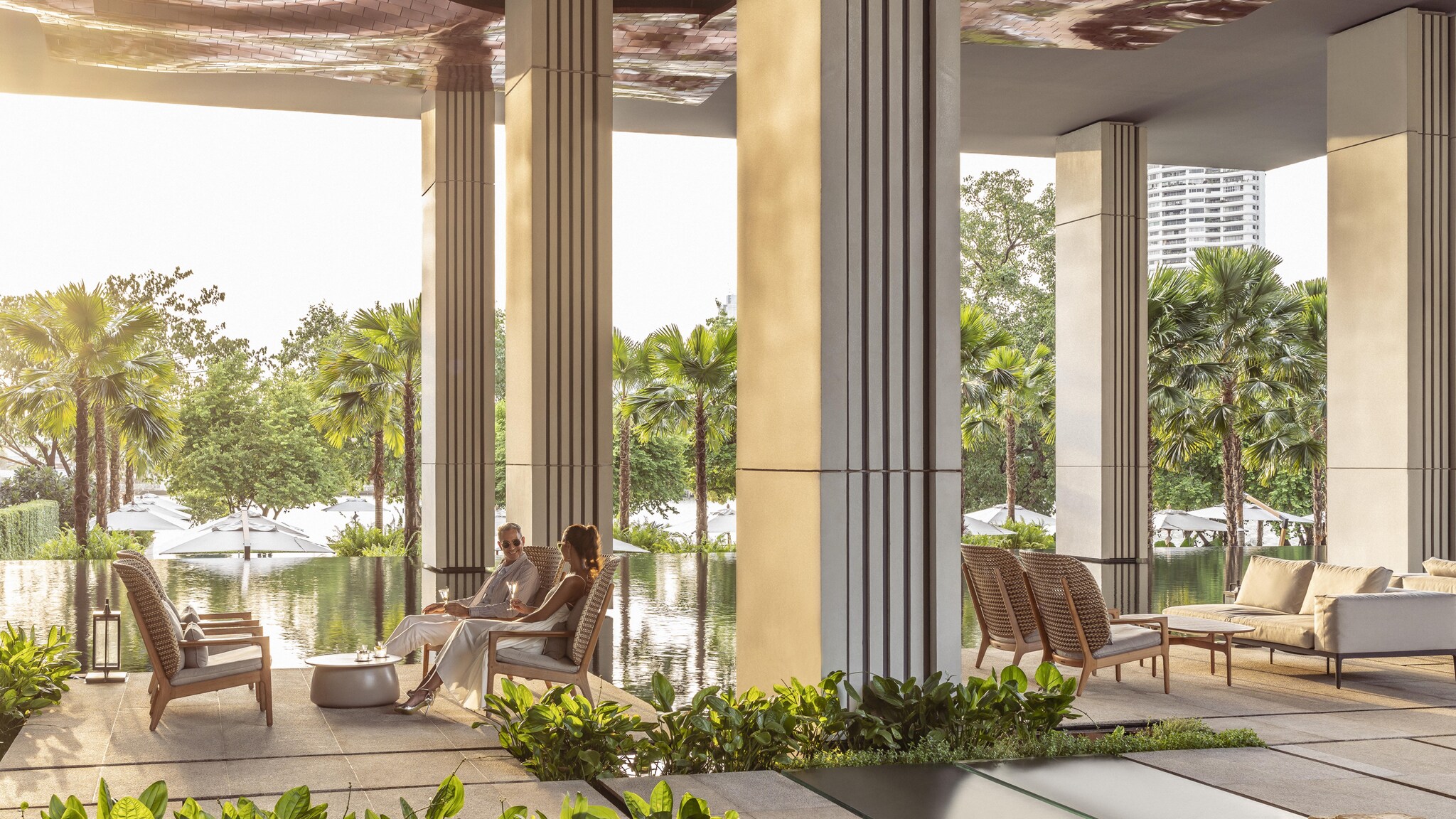 Under the stone overhang of the hotel’s central courtyard, a white couple sits on chairs next to a glassy pool.