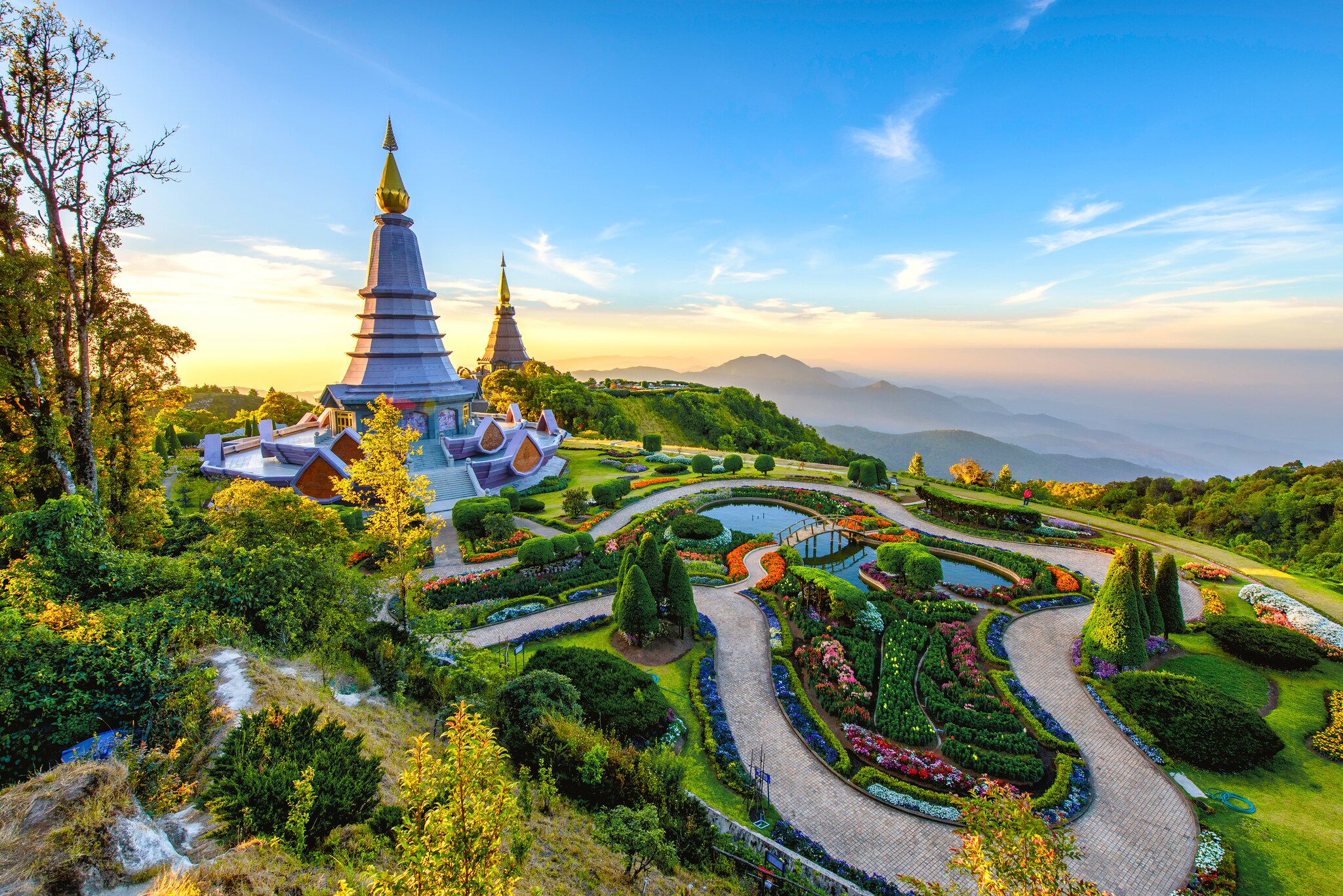 Near the summit of Doi Inthanon, two multi-tiered chedi are surrounded by bright grass, winding pathways, and carefully manicured flowerbeds.