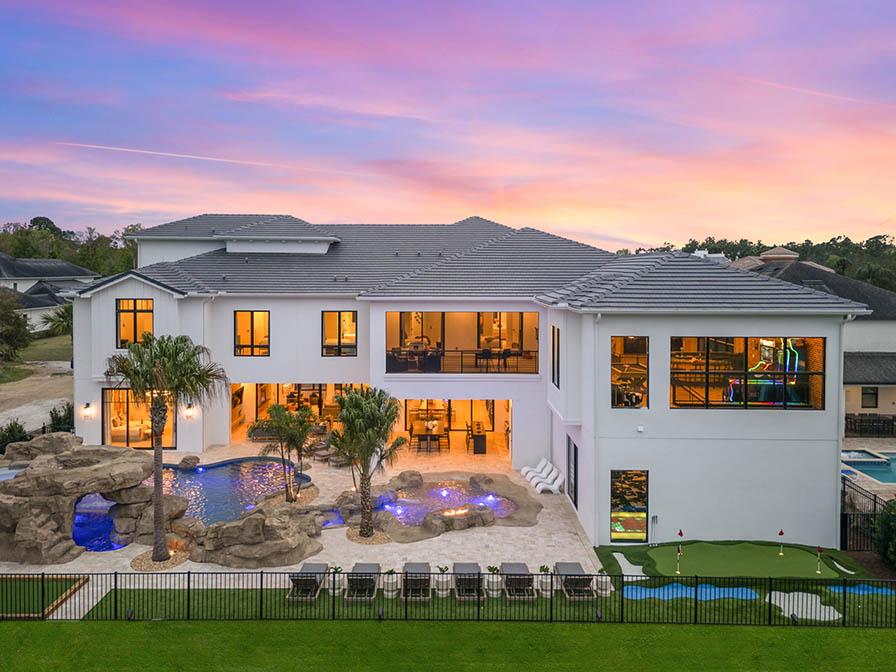 Exterior view of large two-story vacation rental property showcasing outdoor putting green and swimming pool