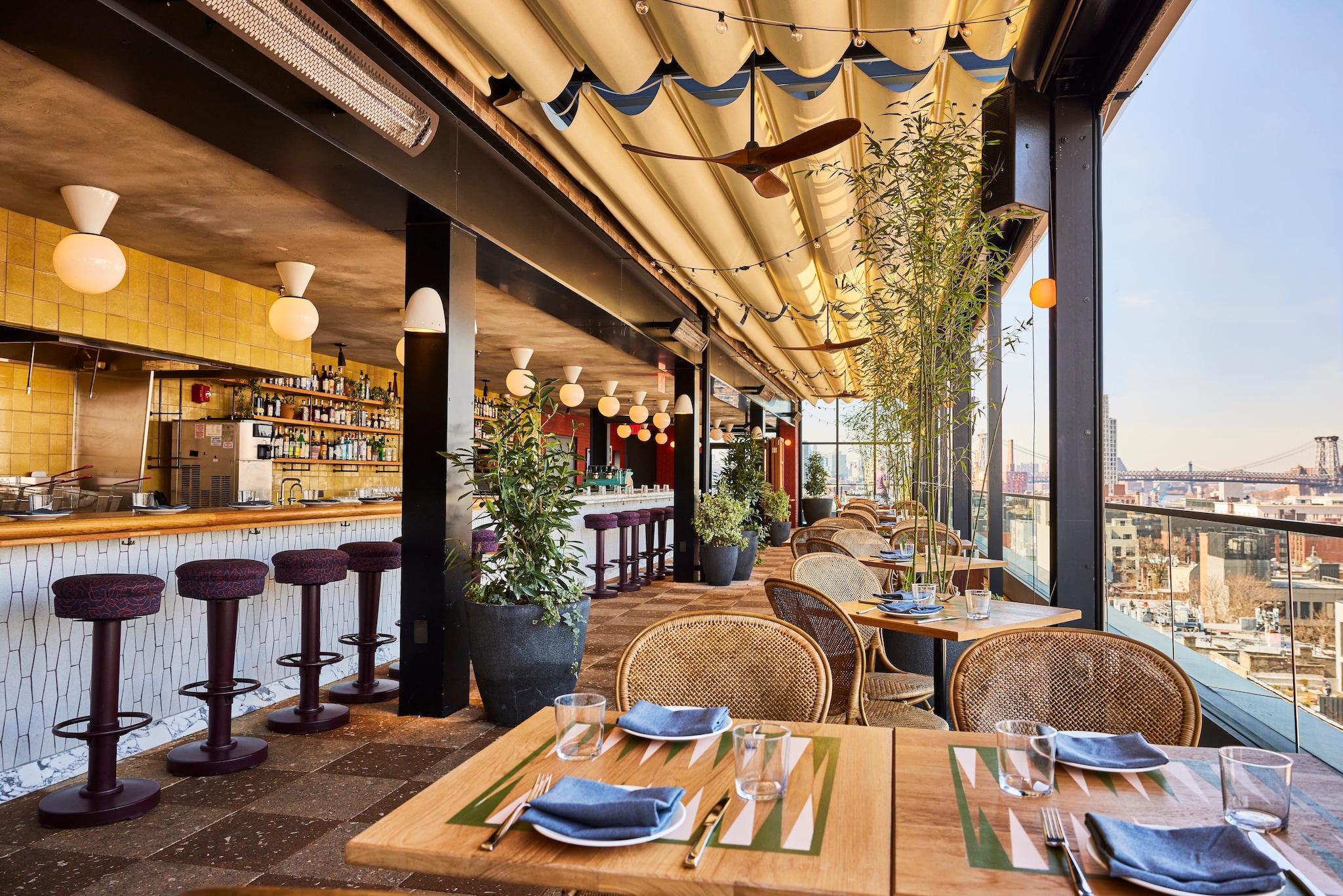 Laser Wolf, the rooftop restaurant at The Hoxton Williamsburg, has wicker chairs, a patterned white bar, and views of the city.