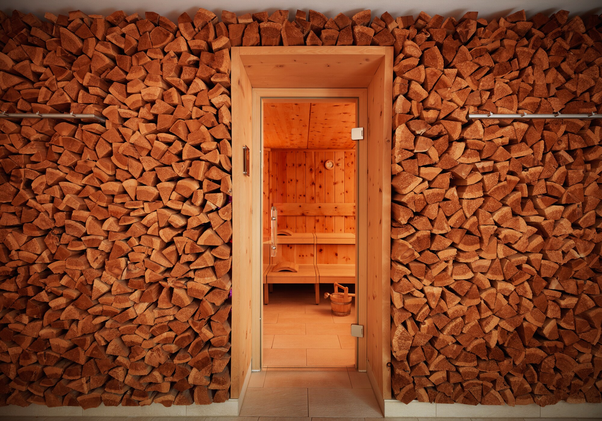 Stacked wedges of wood surround the doorway to the dipiù spa sauna, which has knotted wood paneling and several levels of benches.