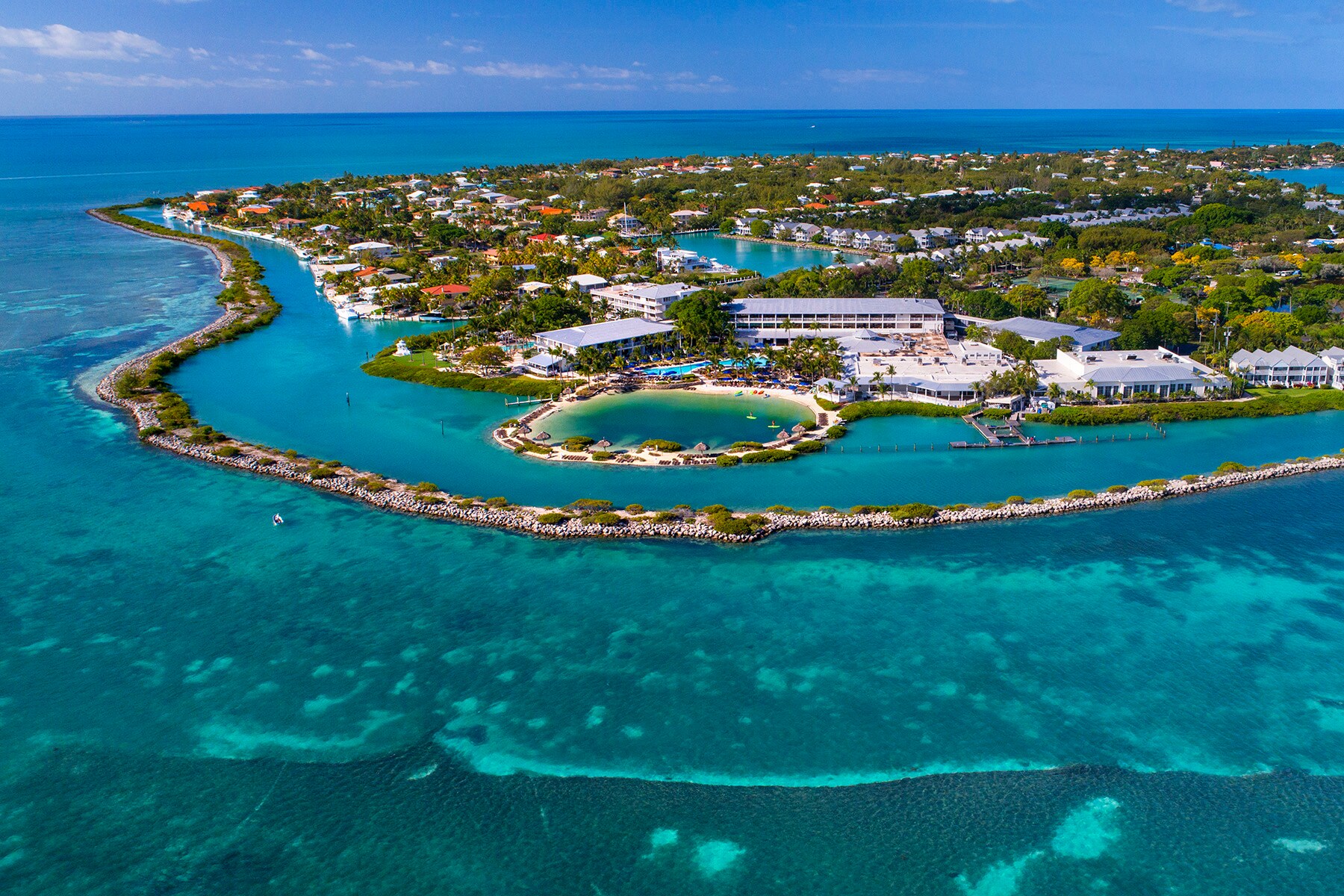 Aerial view of Hawks Cay Resort, a series of low blue-white buildings surrounded by turquoise waters and scattered greenery.