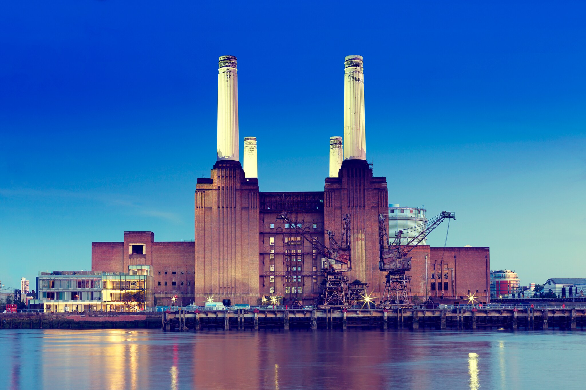 View across the Thames to the Battersea Power Station, a massive brick building which still sports four white smokestacks.