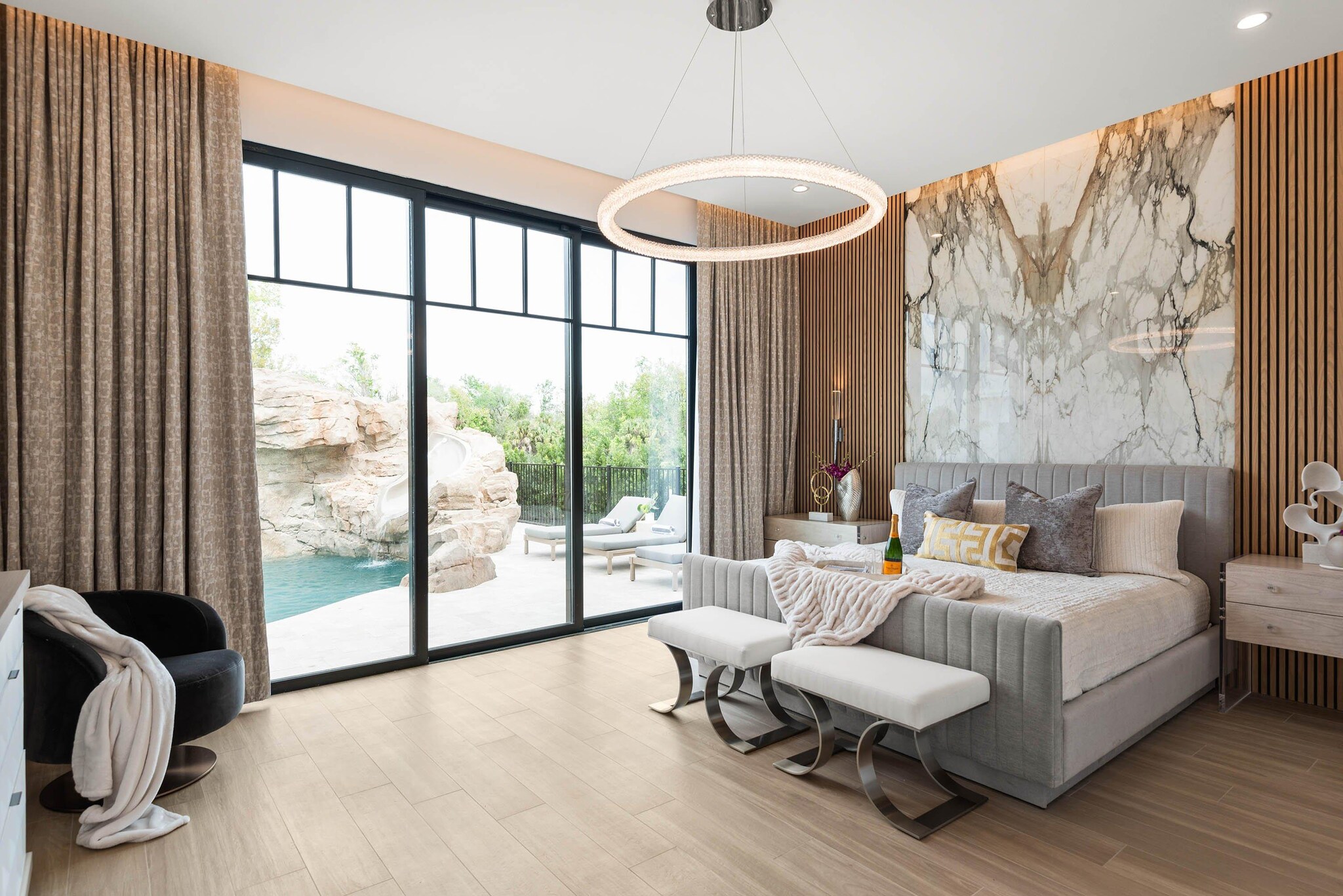 Bright, modern bedroom interior with king bed and patio doors leading to outdoor swimming pool