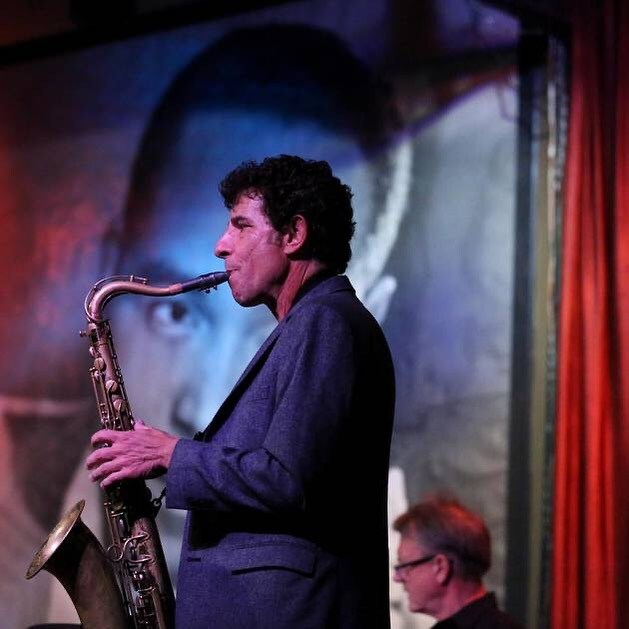 Saxophonist Anton Schwartz, a white man with dark curly hair, plays on the stage at Jazz Showcase.
