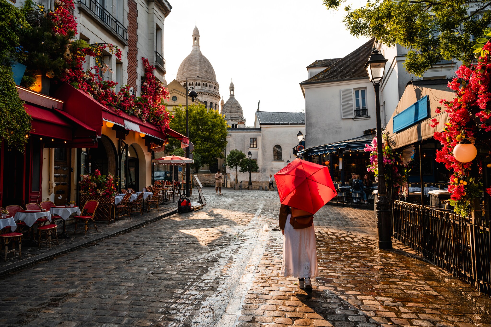 Woman with red umbrella walking in charming street of Montmatre, Paris, France