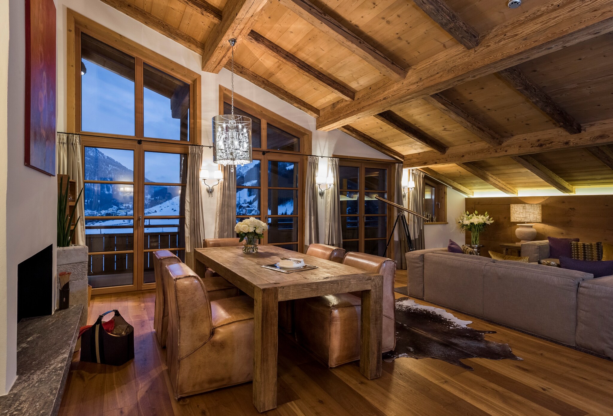 The living room of the master suite has a slanted wooden ceiling and a large wooden table seated with leather chairs.