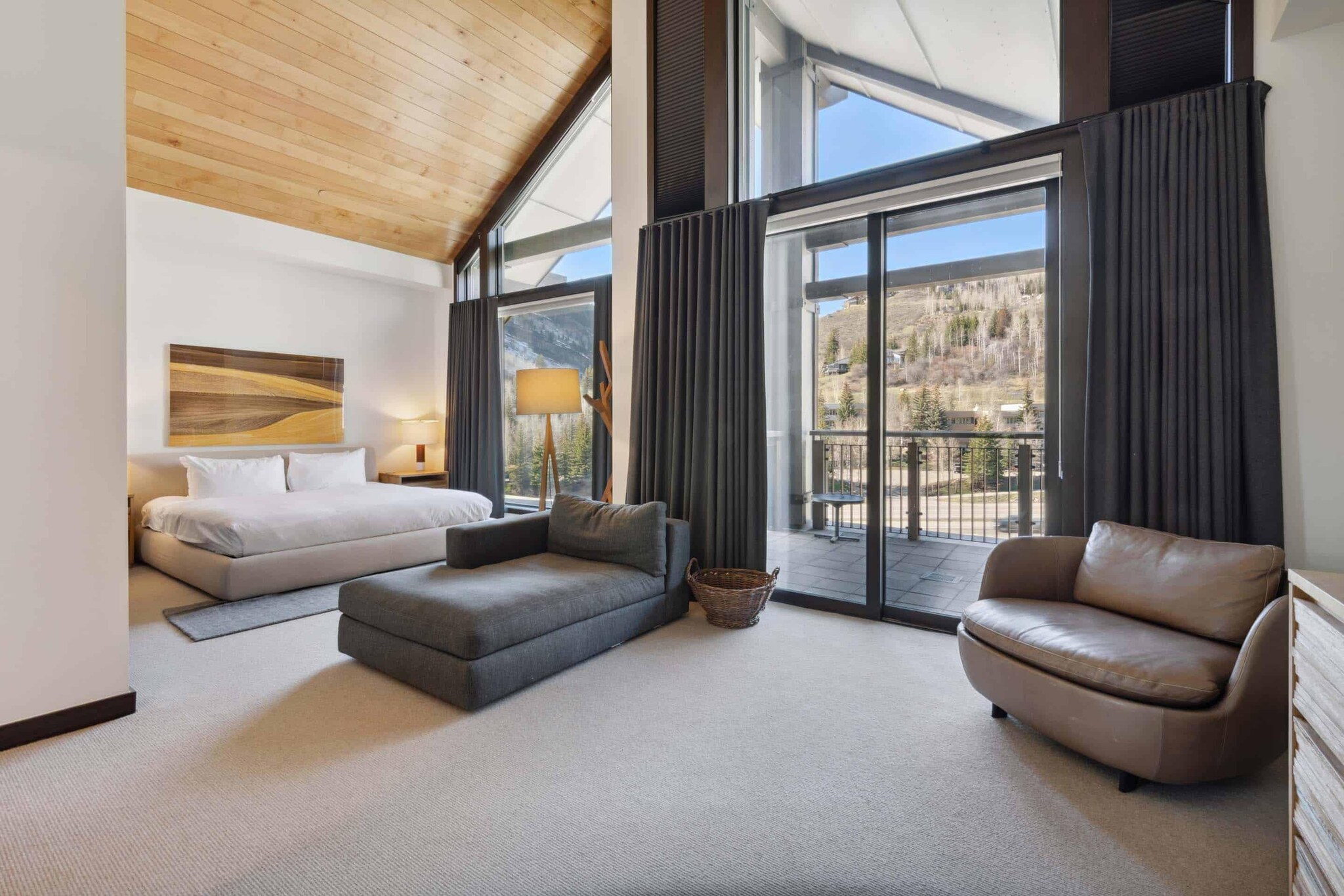 Interior of mountain-lodge style bedroom with mountain view through expansive windows.