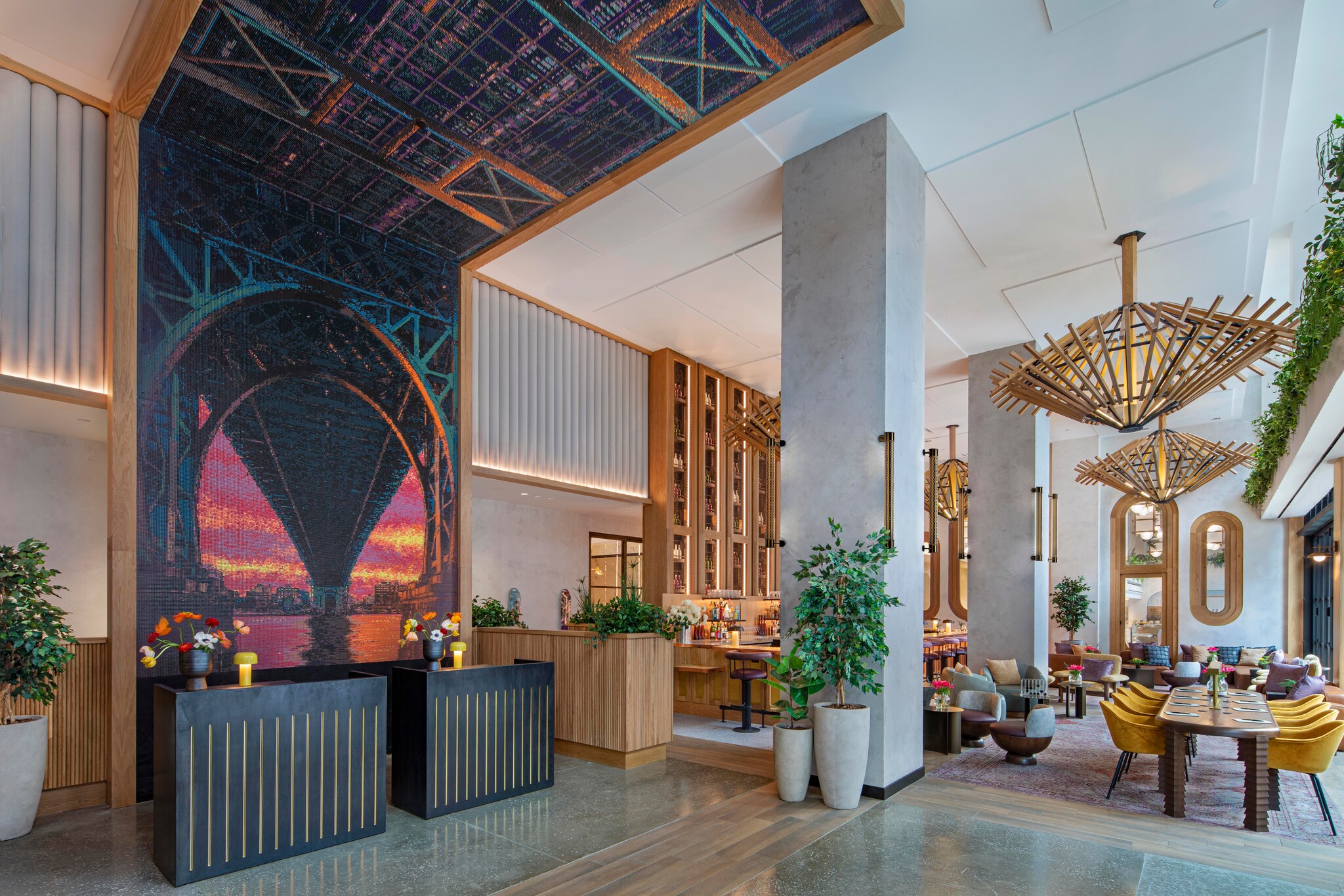The check-in desk sits at the foot of an optical illusion of the Williamsburg Bridge running overhead at sunset. 