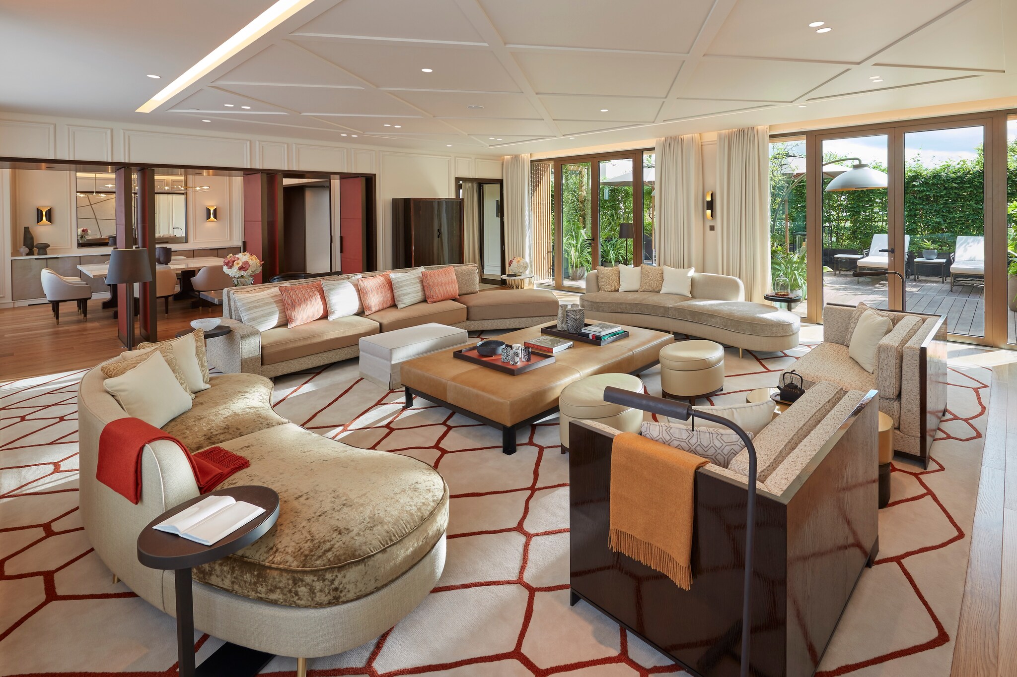 In a Parisian Terrace Suite, five couches form a circle in a large living area, with a dining room and patio visible through doorways.