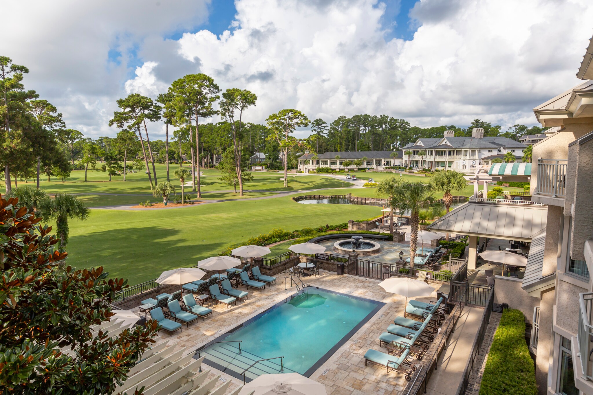 View from an upstairs balcony at The Inn & Club at Harbour Town, looking out over a pool and then the rolling greens of a golf course.