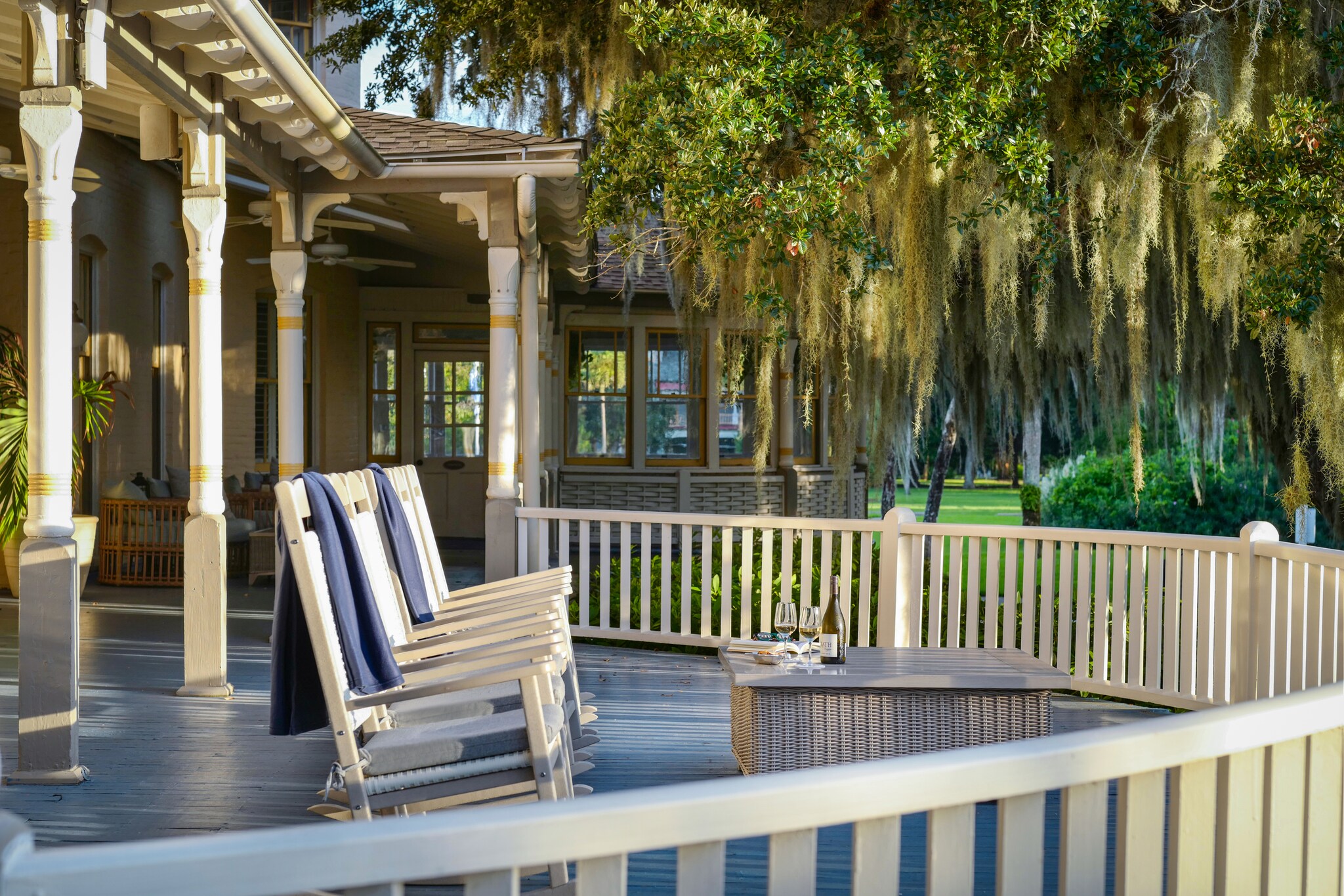 On the riverview varanda, several white rocking chairs draped with towels face out toward trees dripping with Spanish moss.