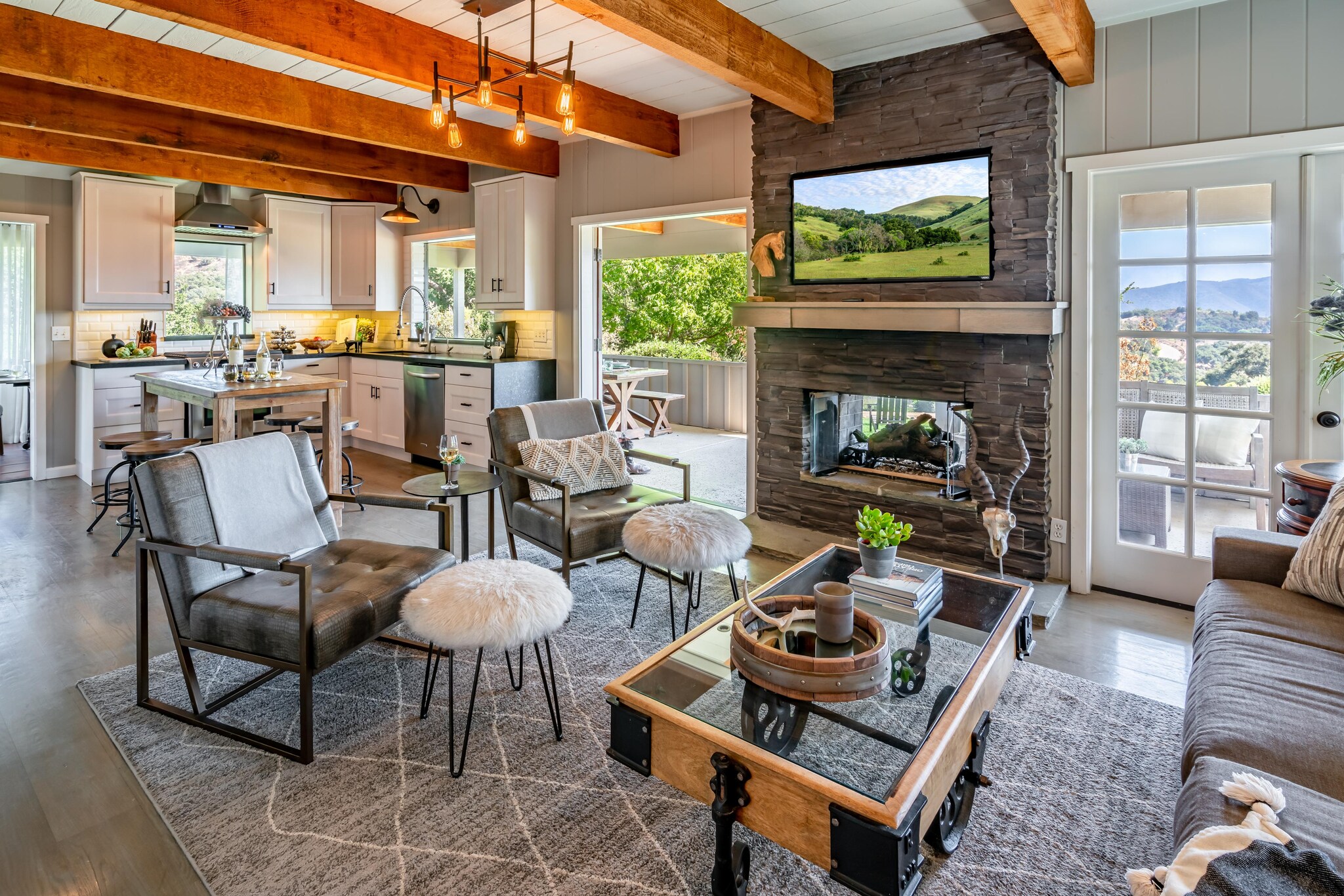 Country cottage interior showcasing living, dining, and kitchen with view of outdoor terrace.