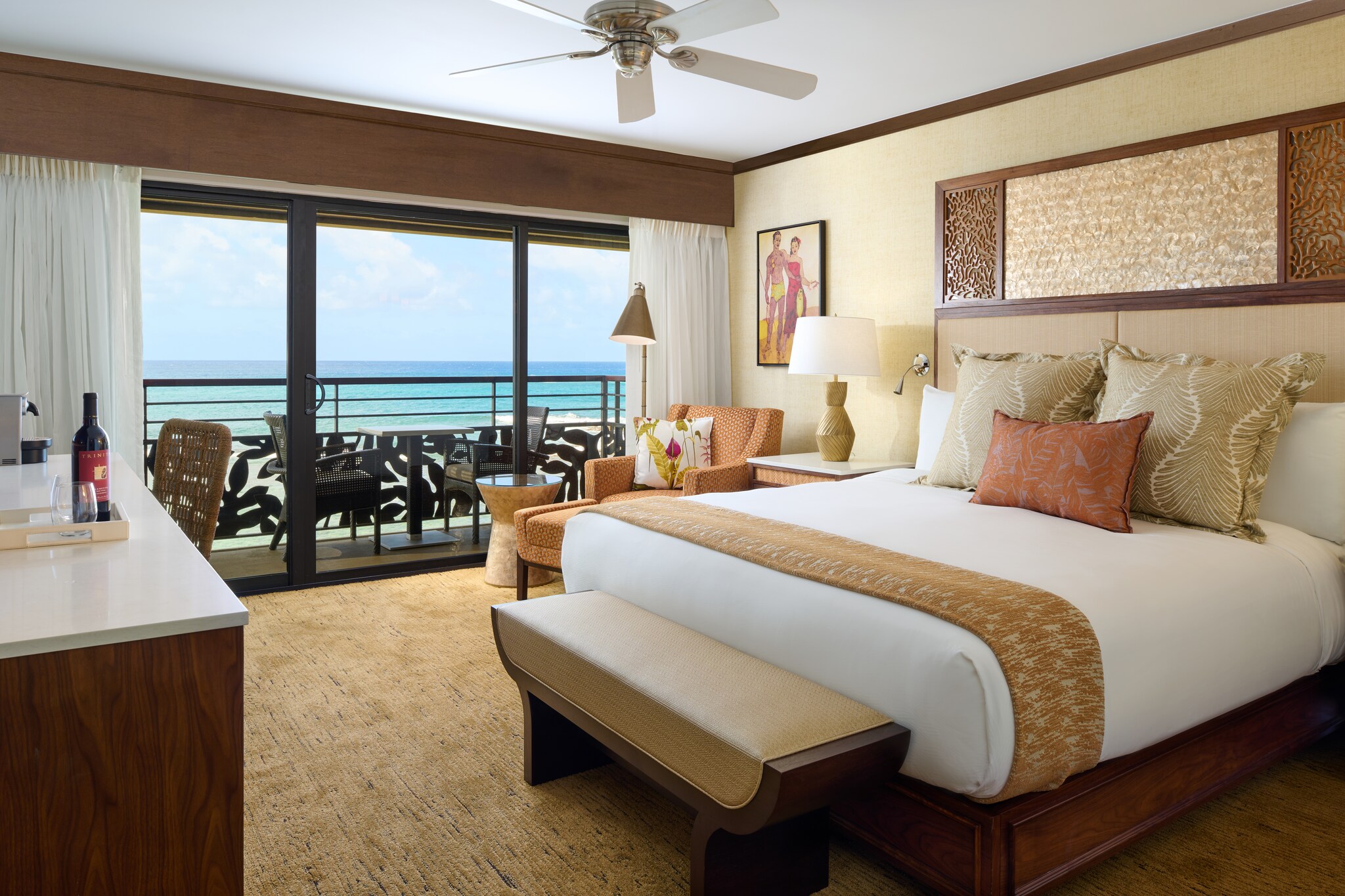 An Oceanfront King Guestroom is decorated in gold, tan, and orange. The far wall opens onto a balcony overlooking the water.