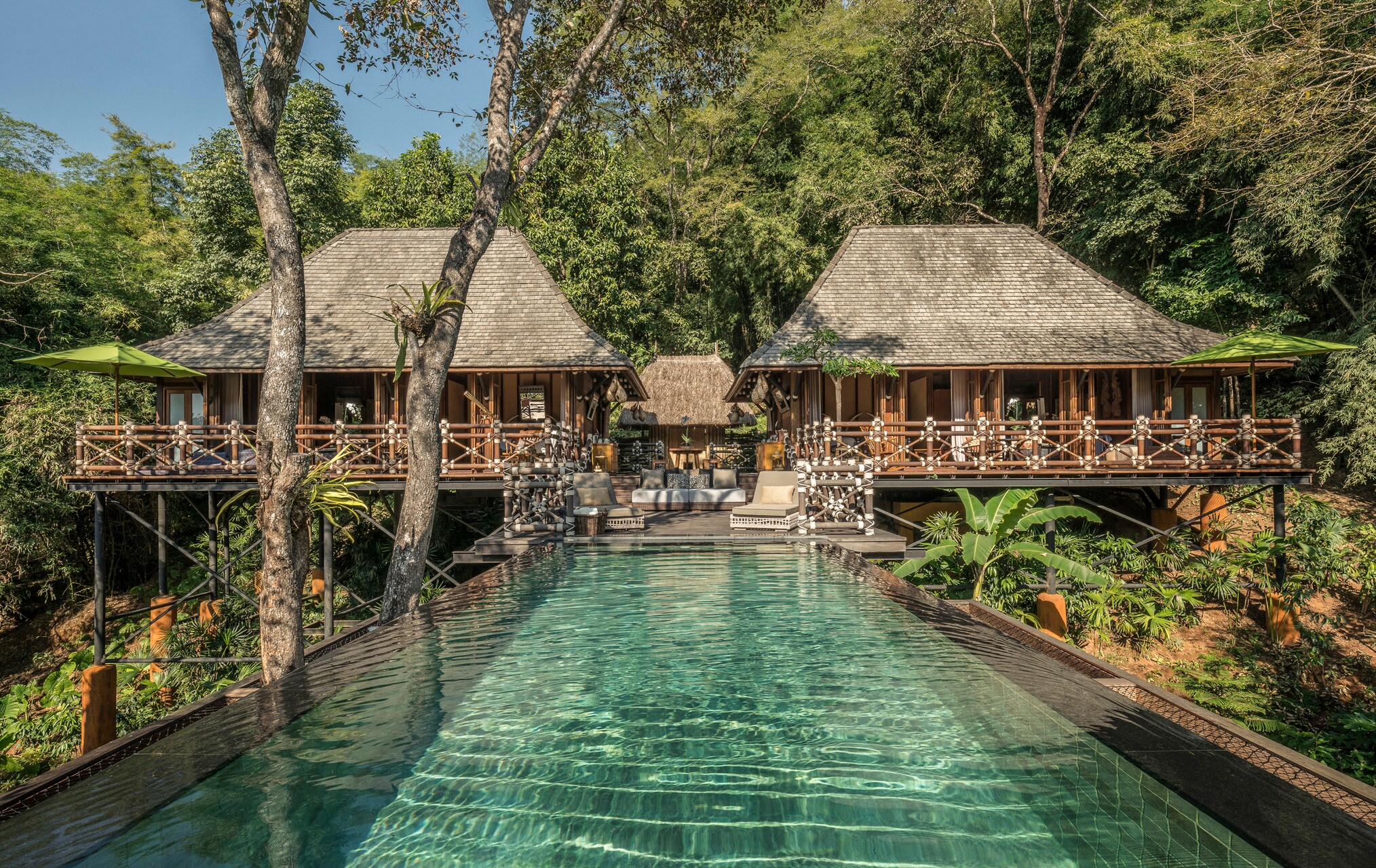 Looking across a rectangular infinity pool towards the two-bedroom explorer’s lodge, which has trapezoidal roofs and a wraparound porch.