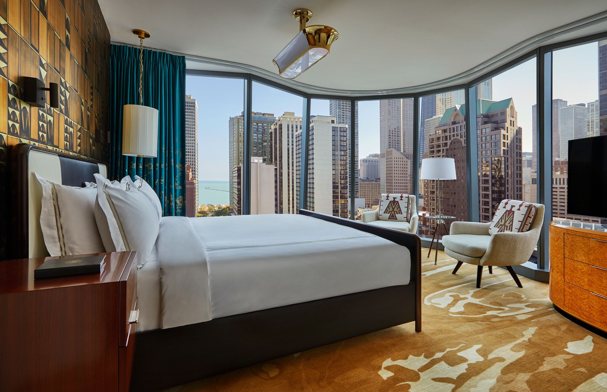 The bedroom of a Lakeview Suite is decorated with bold yellow patterns and shows off city views with two walls of floor-to-ceiling windows.