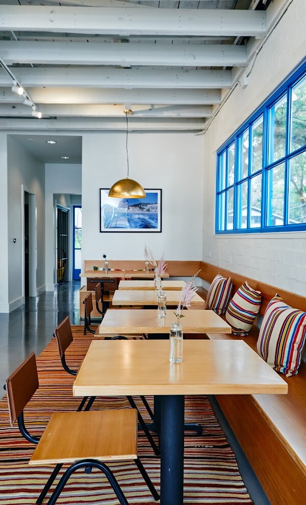 The bright interior of Birdie nestles small tables against a bench built into one wall, with striped cushions for extra comfort.