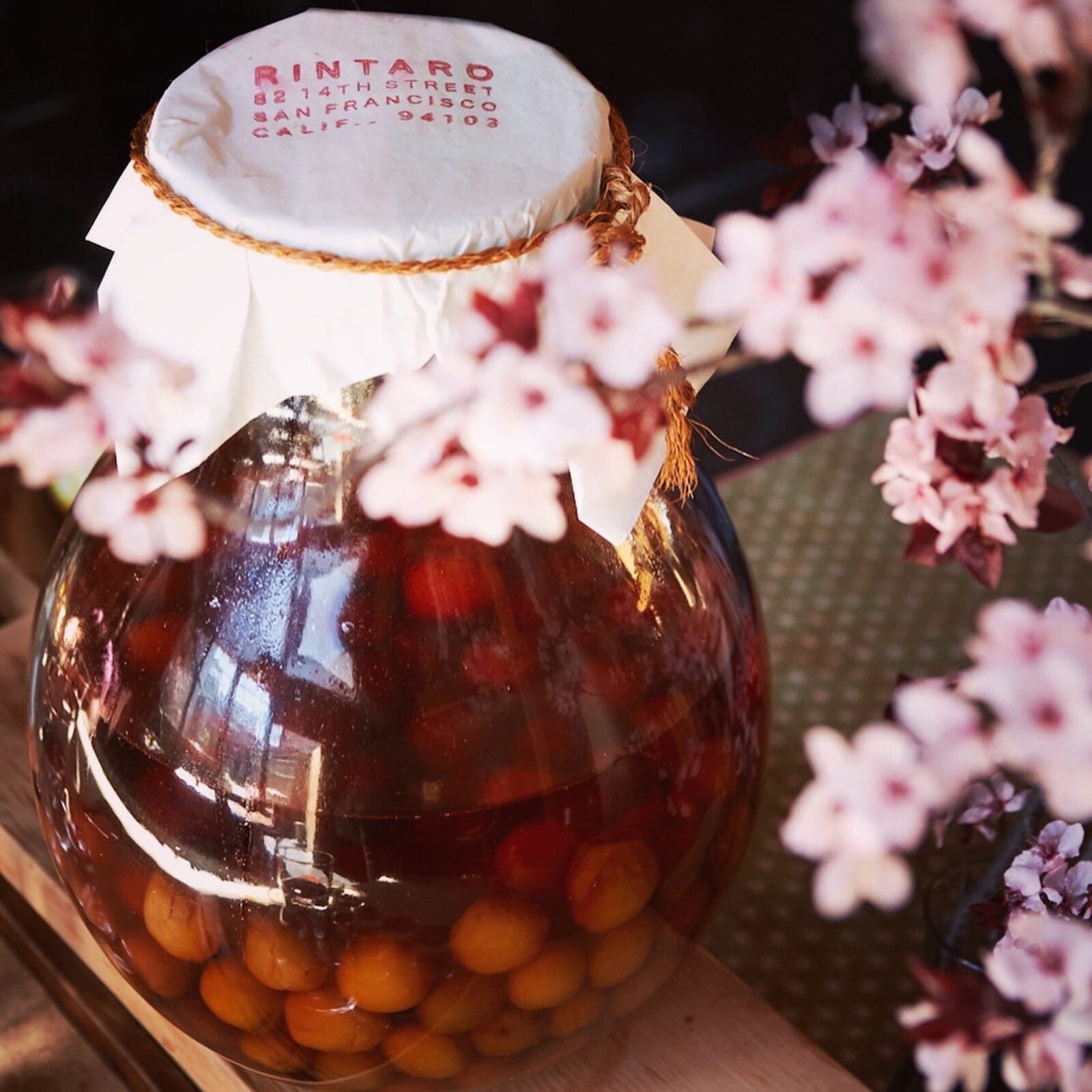 In a pear-shaped glass jar topped with paper stamped with the restaurant name and address, ume plums stew in liquor to make umeshu.