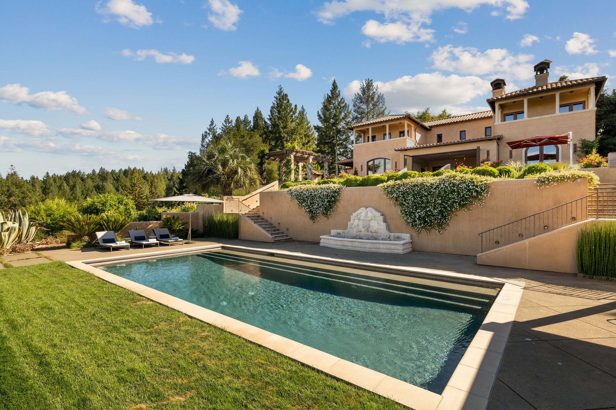 Exterior view of two-story home backyard featuring large patio and outdoor swimming pool