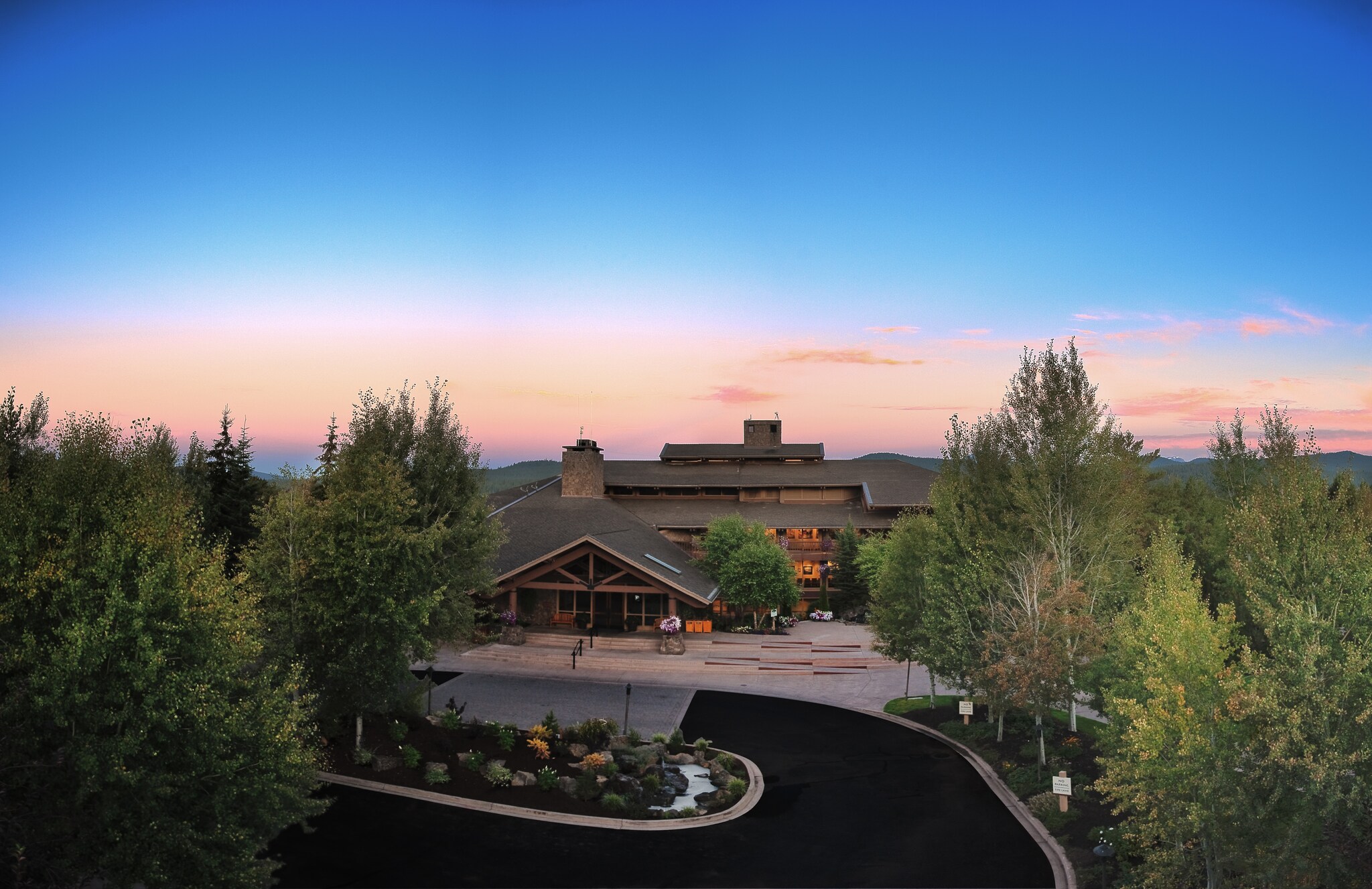 Aerial view of the brown, multi-tiered lodge in the early evening with the sun just starting to set.