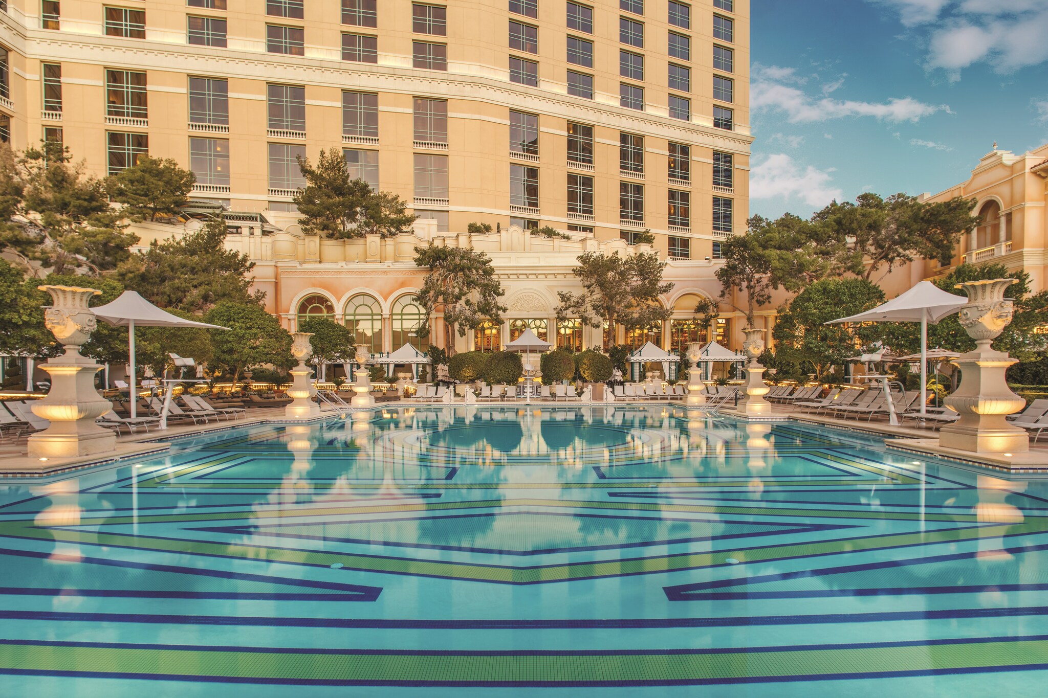 The Bellagio pool is wide, with geometric tile mosaics along the floor. It is fringed by lounge beds, umbrellas, and Italianate urns.
