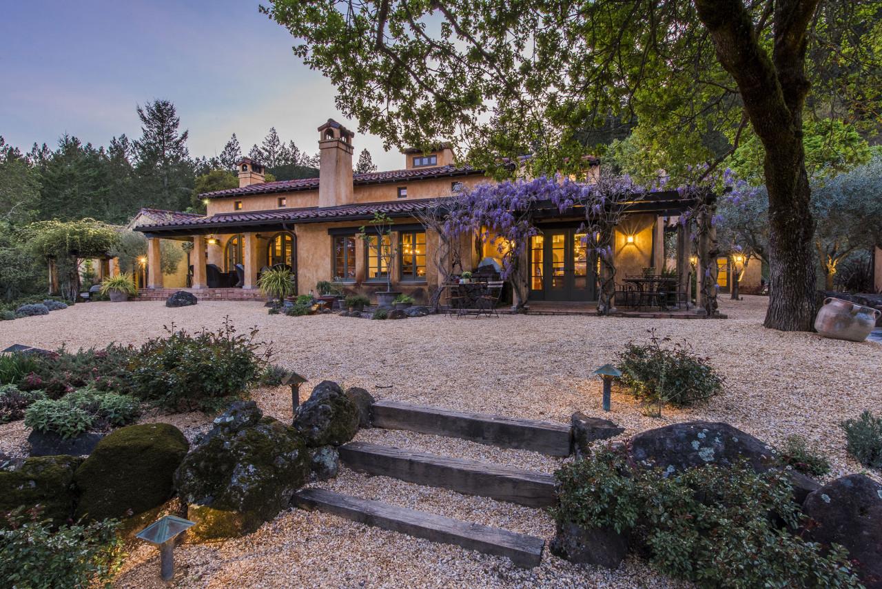 Exterior of Spanish style ranch house set amongst mature trees.