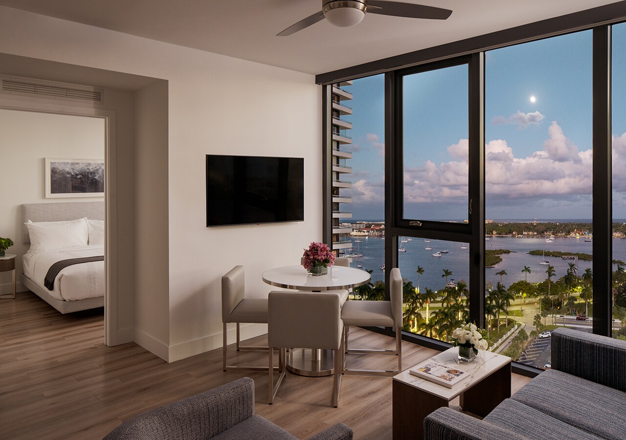  A two-bedroom suite at AKA West Palm has a television, a round table, and floor-to-ceiling windows overlooking the Intracoastal waterway.