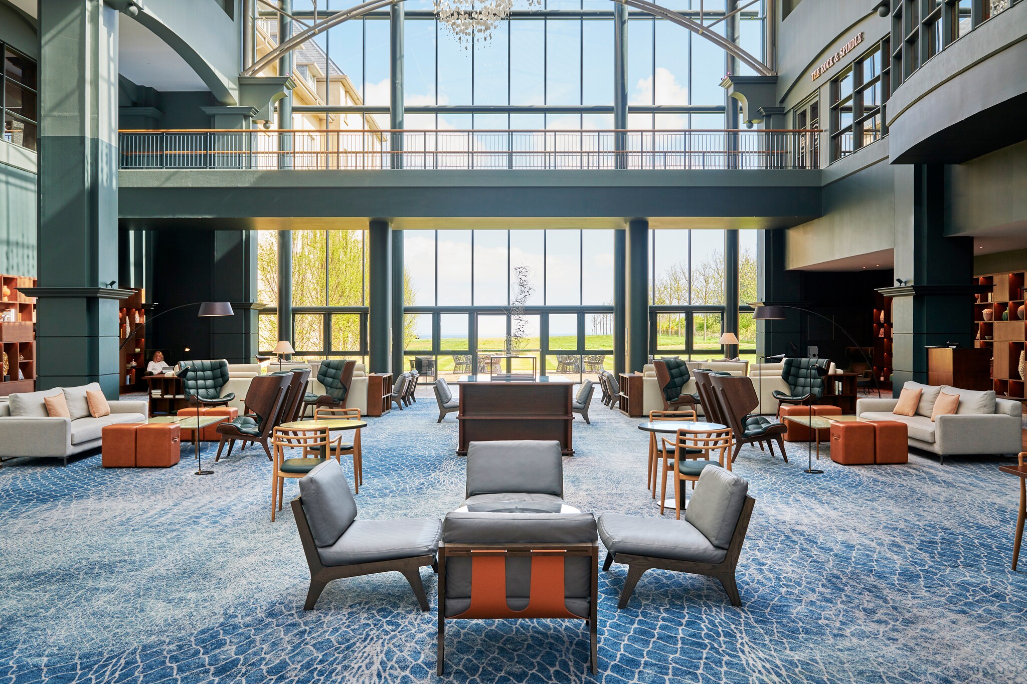 The Fairmont St Andrews atrium is large, with high ceilings and a wall of high glass windows. The blue carpets are patterned like netting.