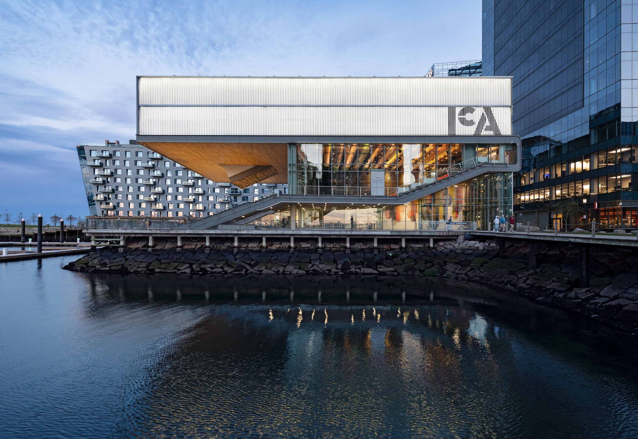 Exterior view of the Institute of Contemporary Art, with a large translucent top floor hanging over two smaller glass-walled floors.