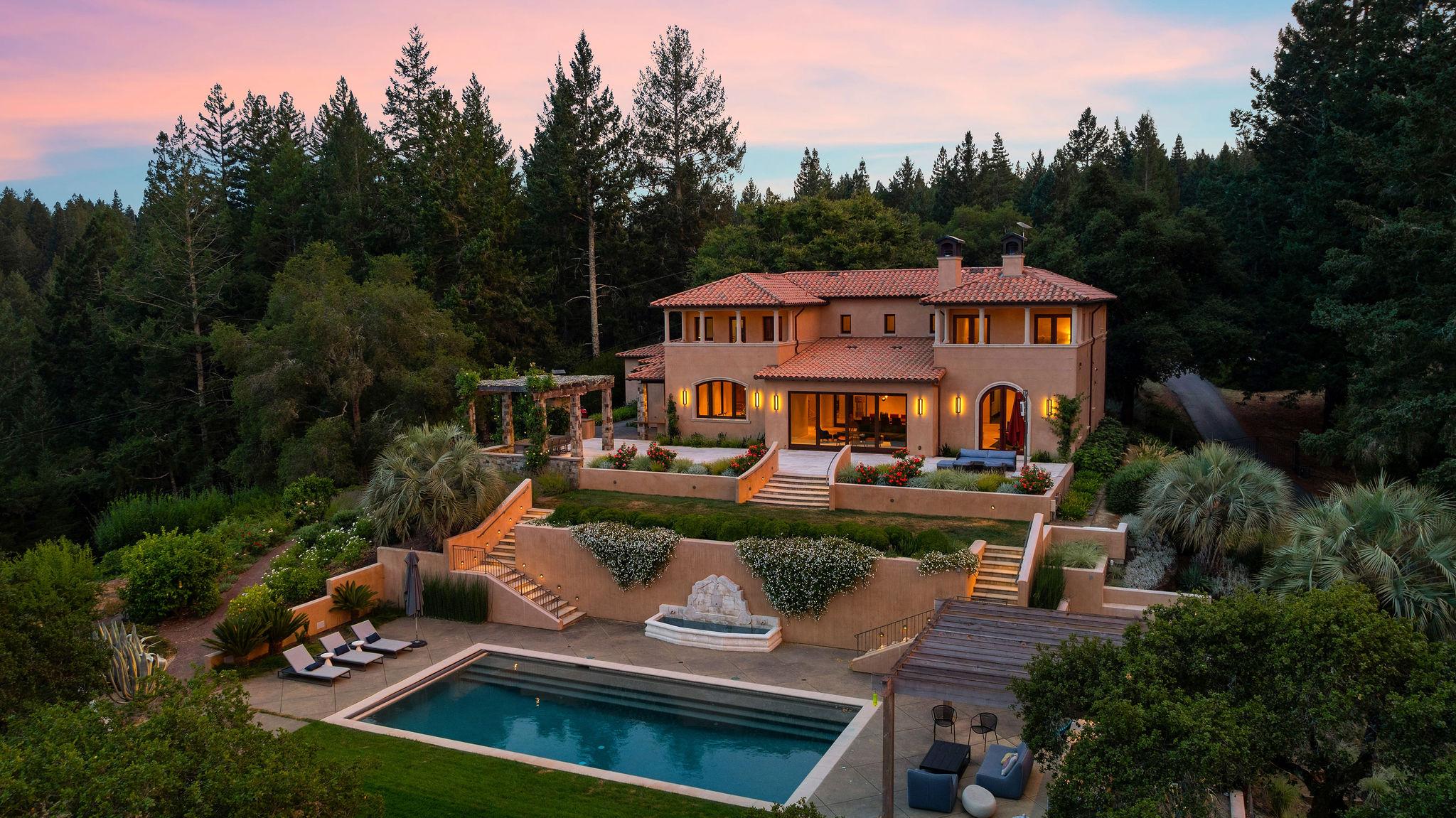 Aerial view of two-story home backyard featuring large patio and outdoor swimming pool