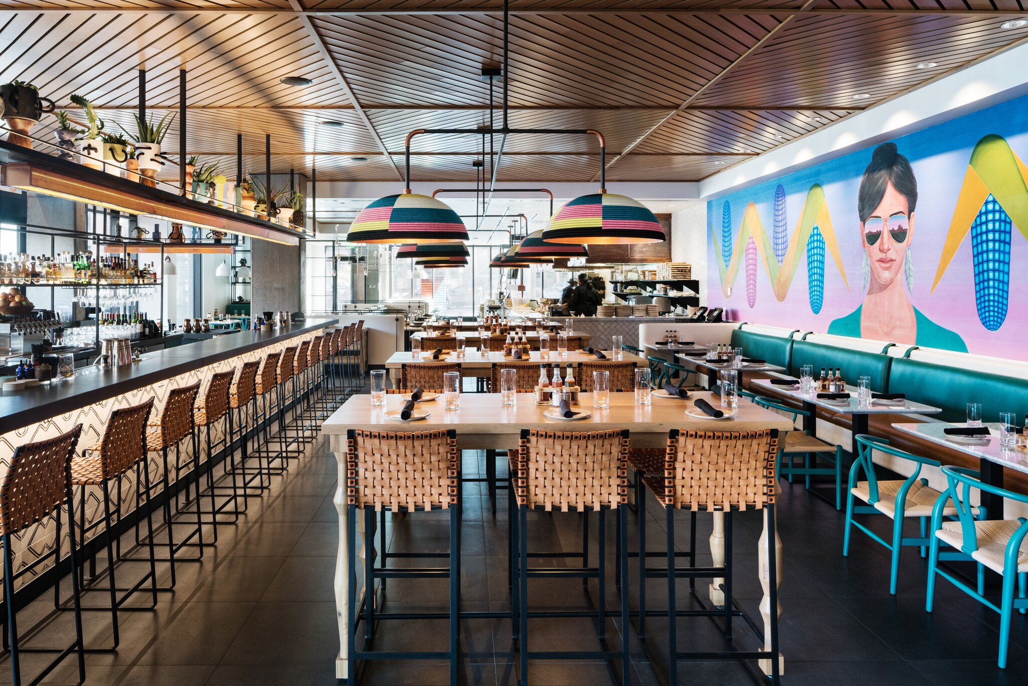 Kachina has artistic details, with colorful woven lampshades, wicker-backed chairs, and a bright vaporwave-style mural of a woman and corn.