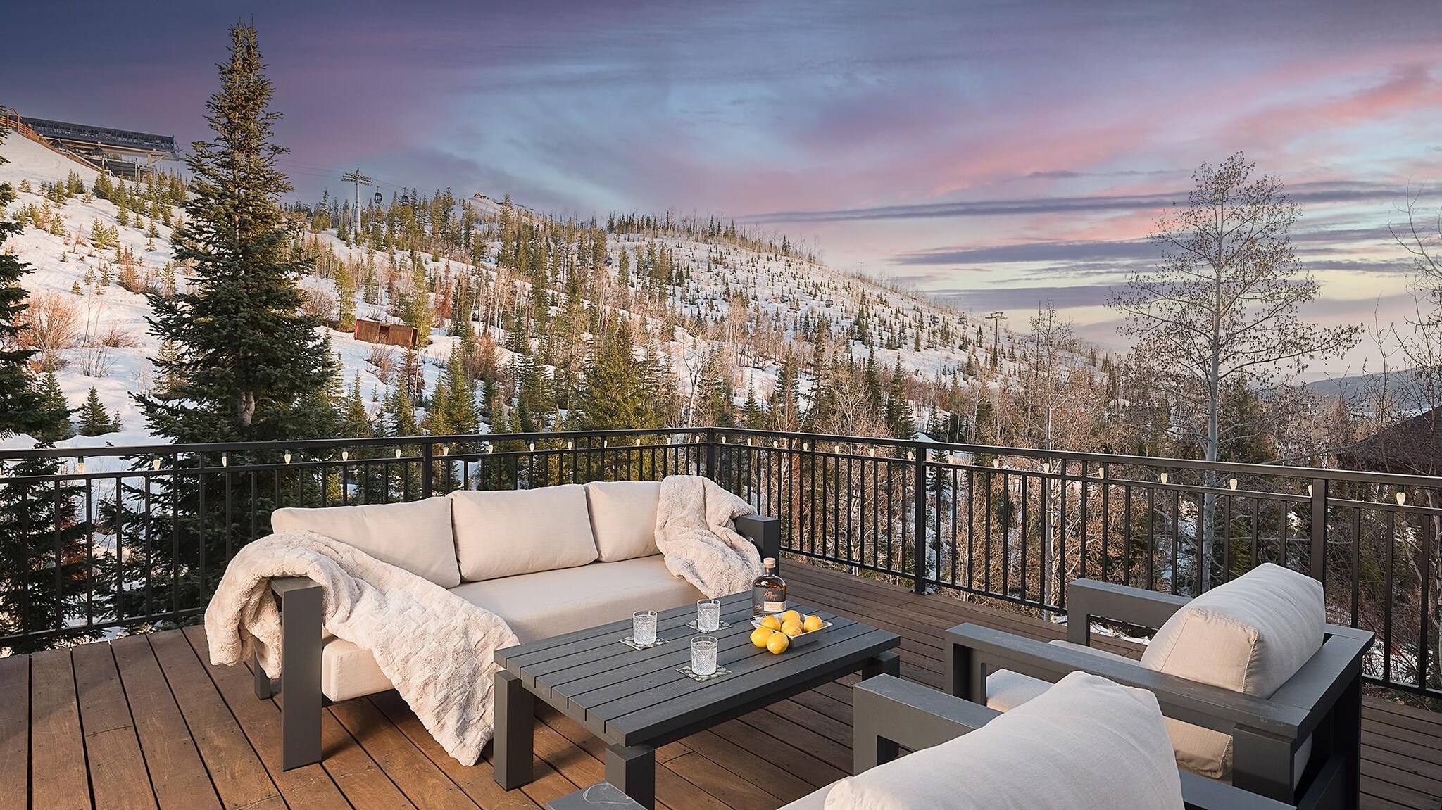 Balcony with lounge seating overlooking snow-covered mountains.