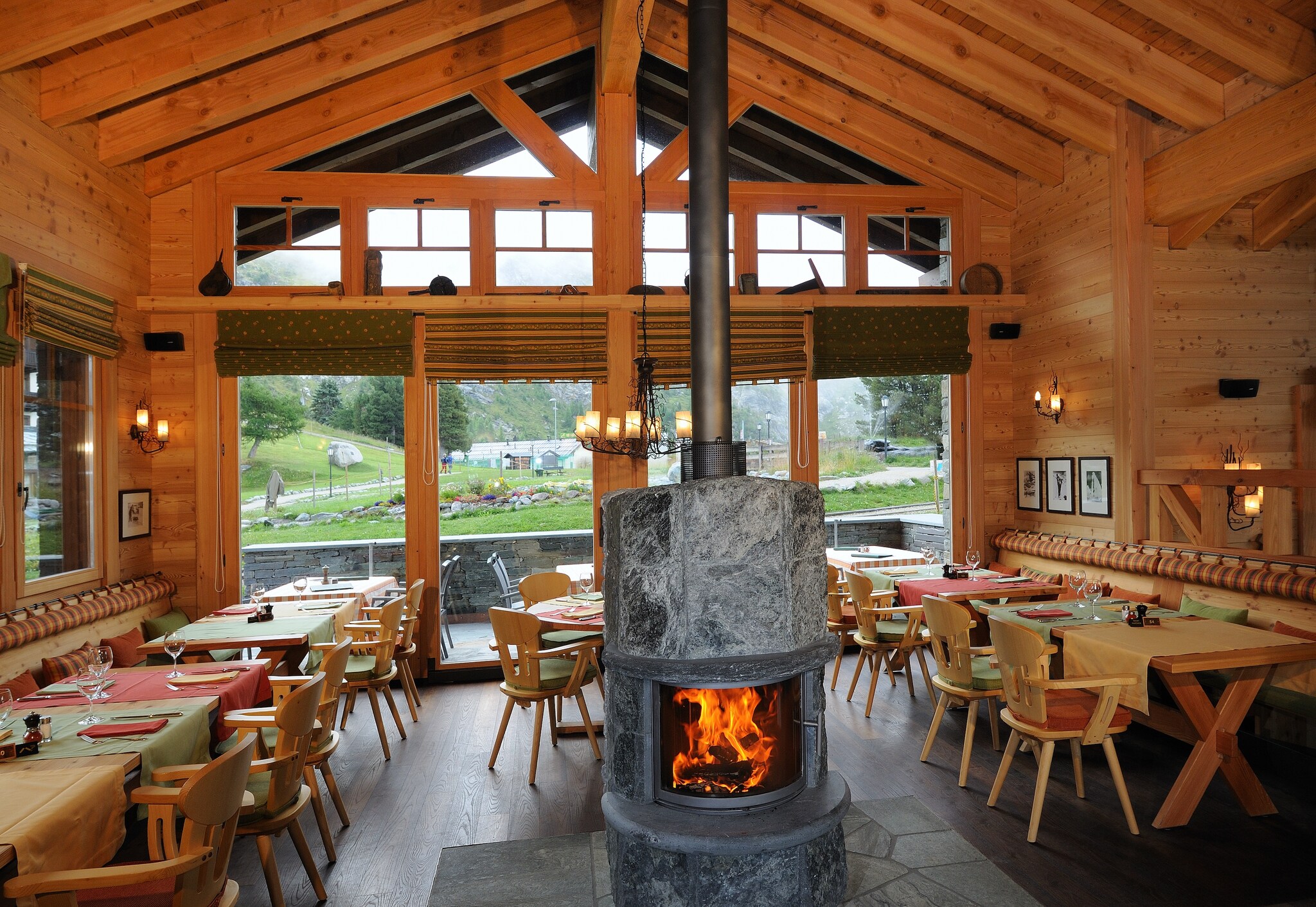 The dining room of Ristorante Al Bosco has knotted wood walls, and its wooden tables are situated around a circular fireplace and fitted.