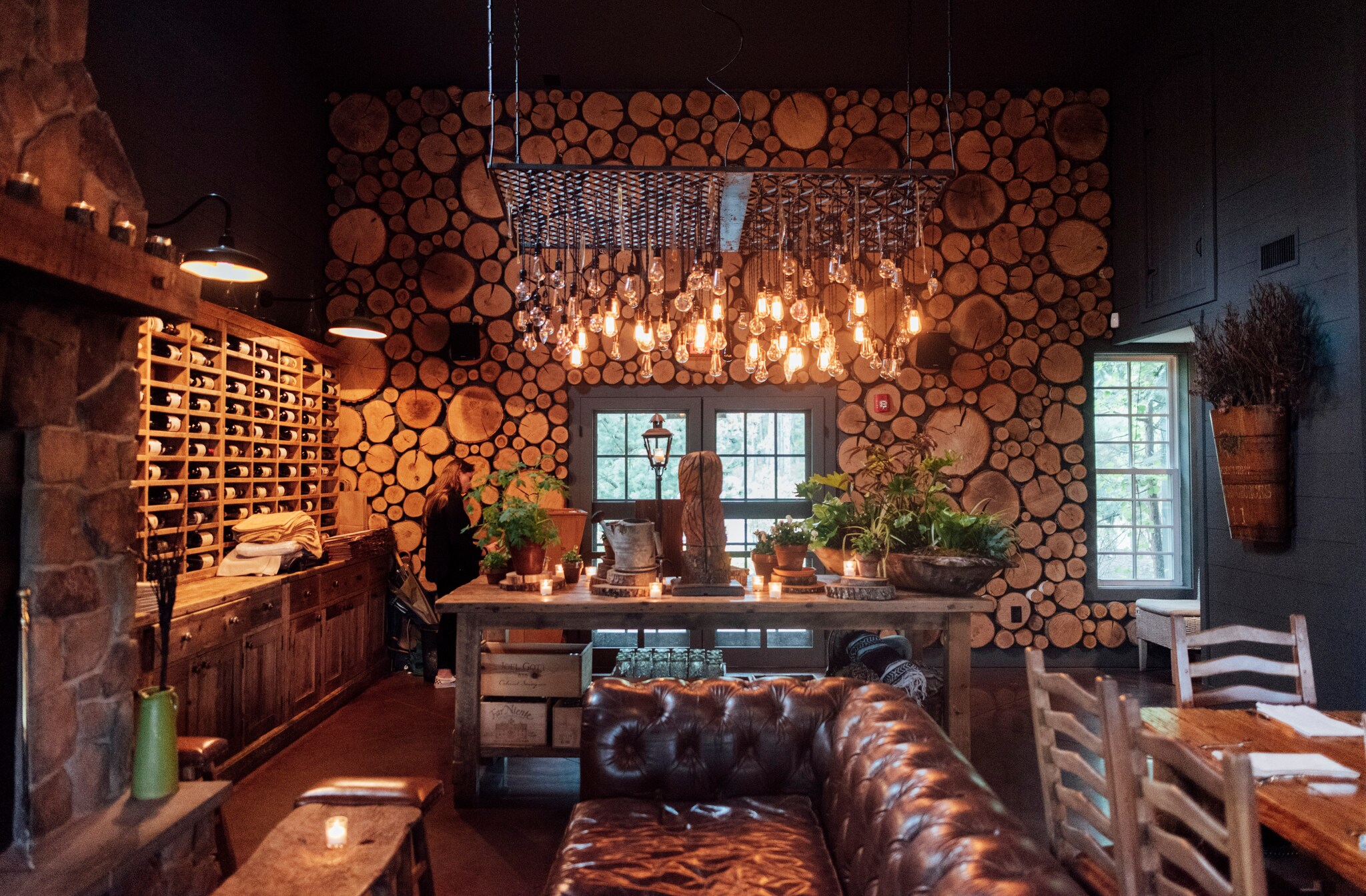 One wall at the Earth restaurant is made of cross-sections of logs, and a wooden table is filled with potted plants next to a leather couch.