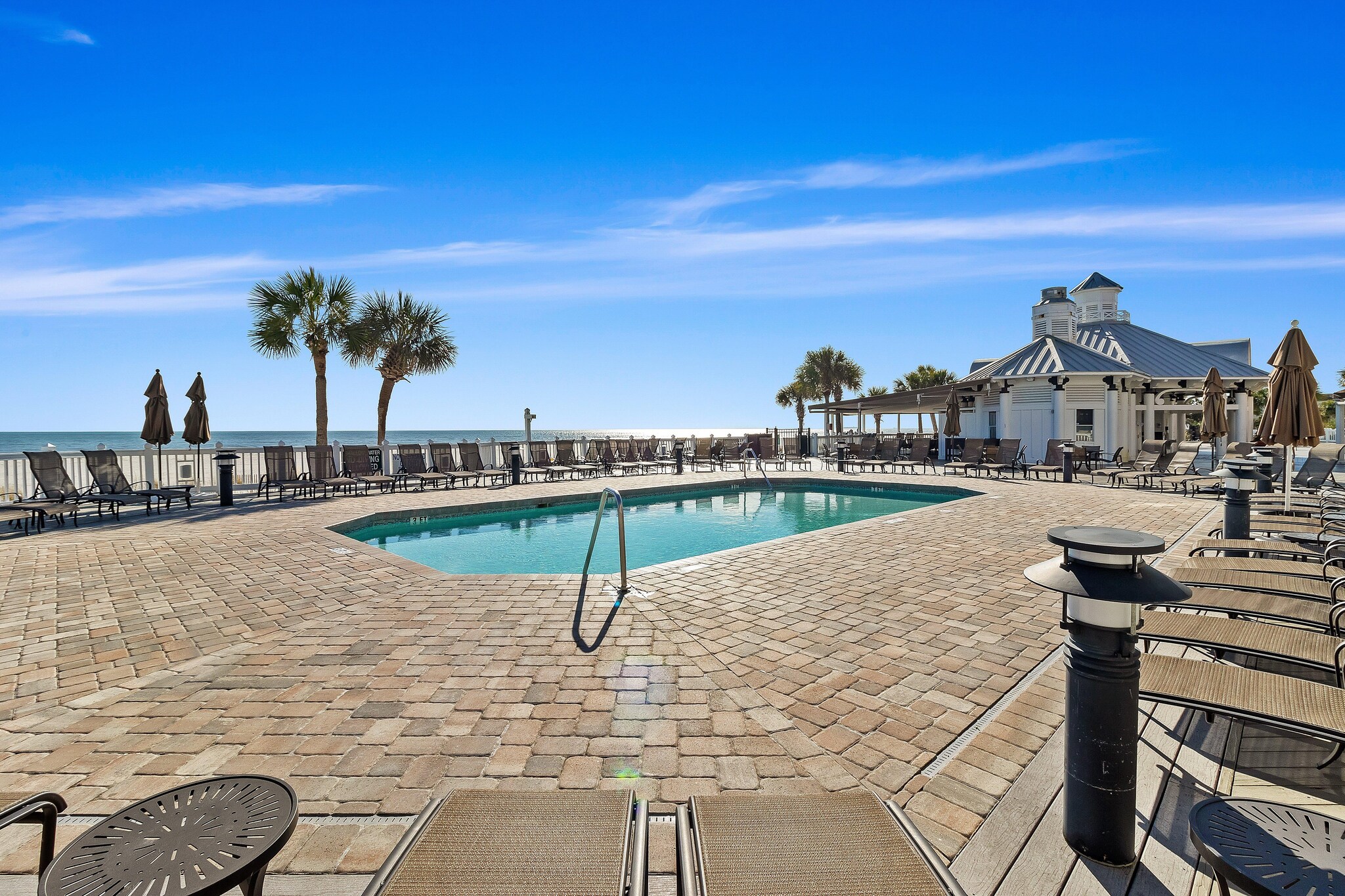Large swimming pool and deck area of community pool near beach.