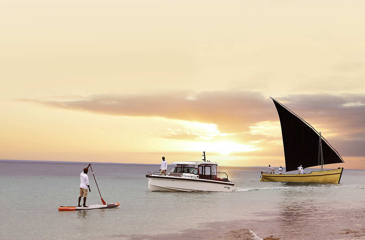 Paddle boarder and boats at sunset