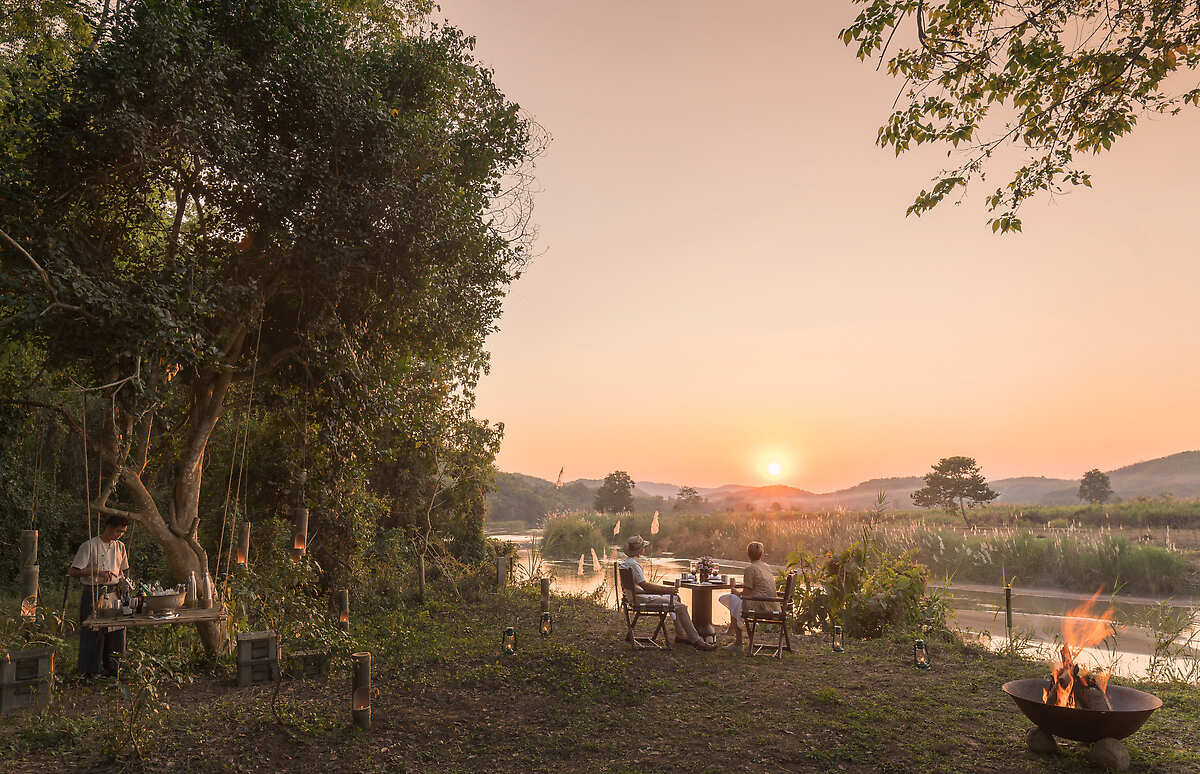Outdoor dining near river at sunset